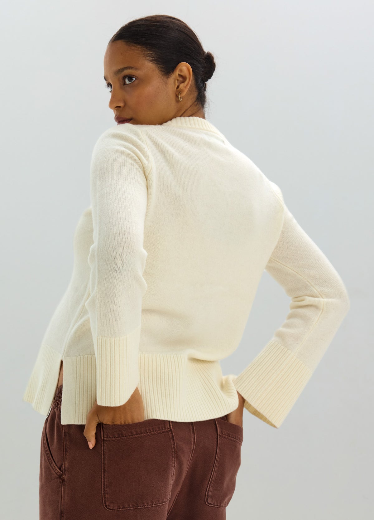 Cream-colored ribbed maternity cardigan with long sleeves and side slits, modeled by a pregnant woman.