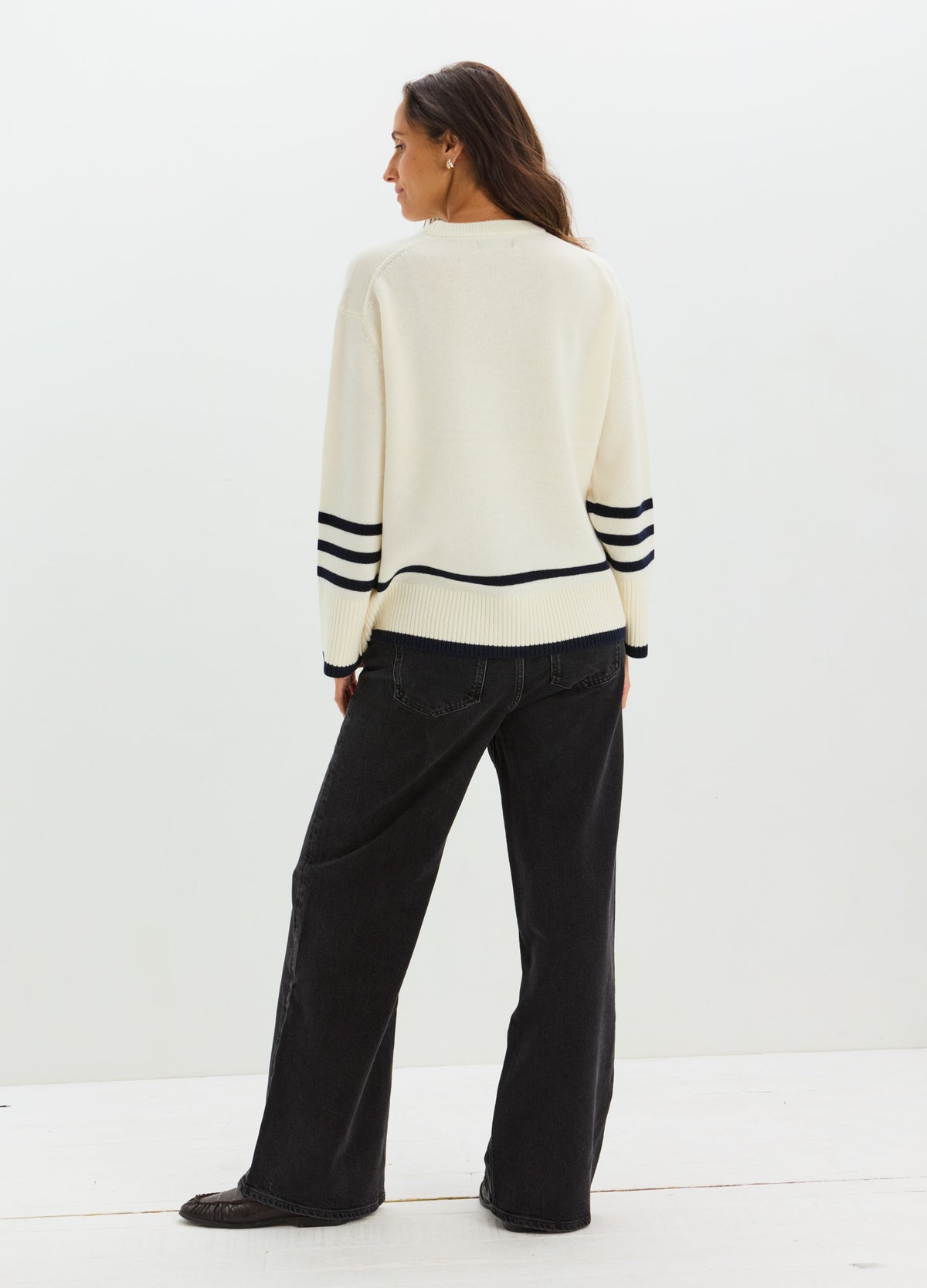 Cream maternity nursing sweater with black stripe details on sleeves and hem, worn with loose black pants.