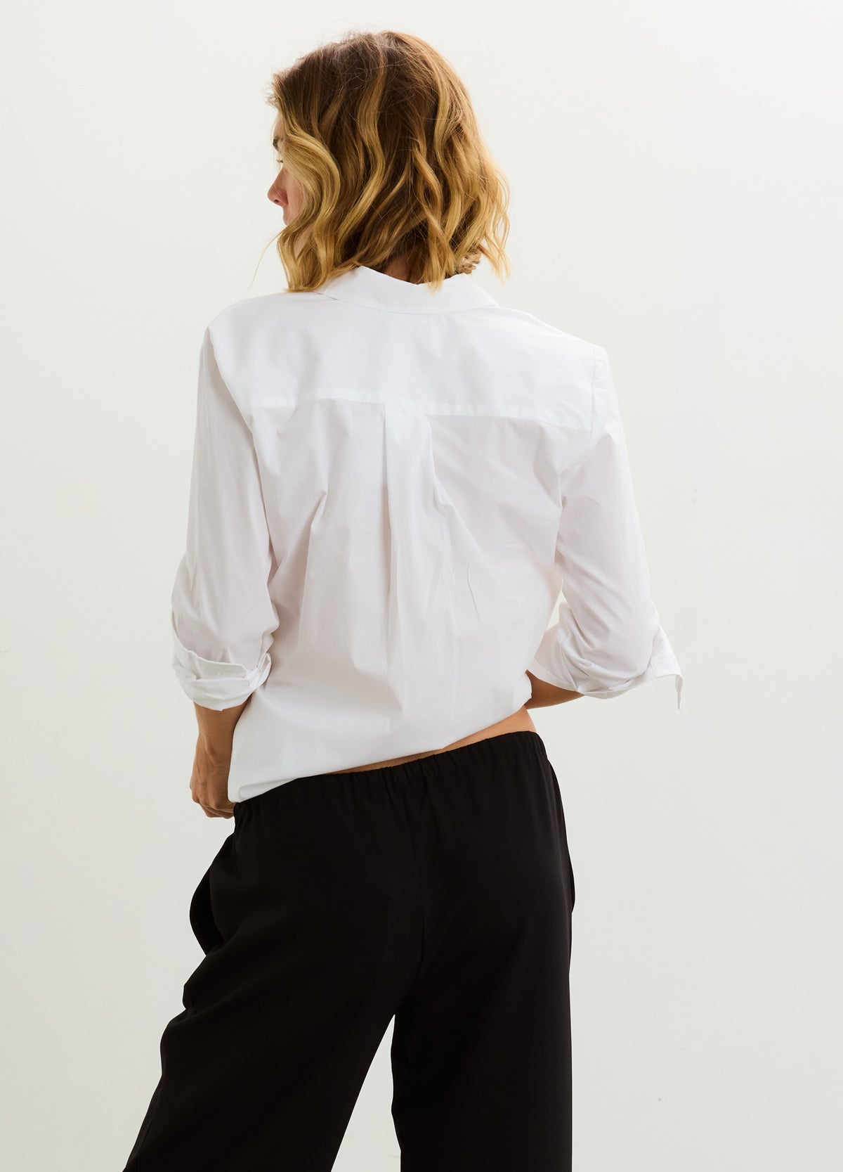 White long-sleeve buttondown shirt with relaxed fit, worn by a pregnant model from the back.