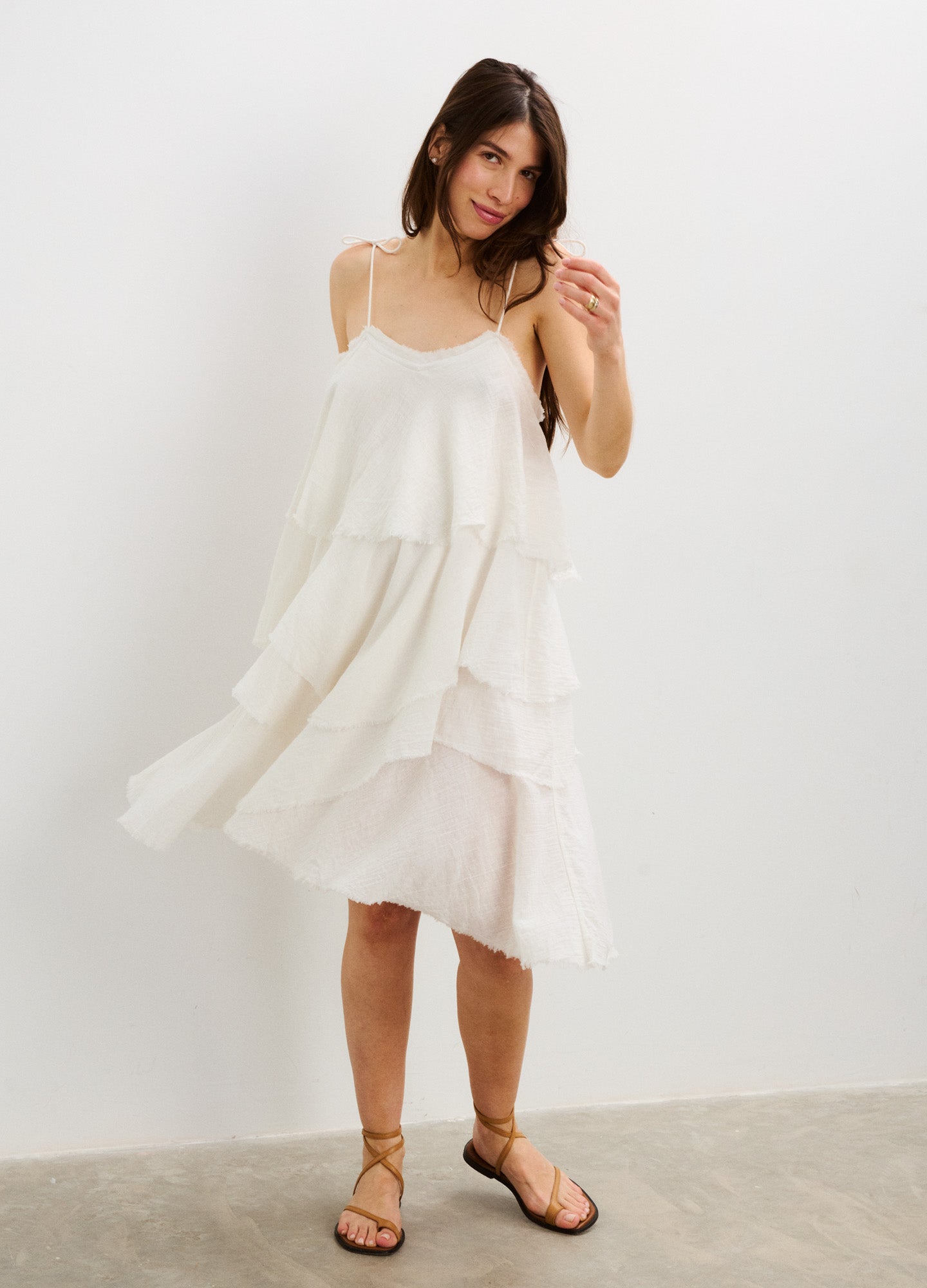 White tiered sleeveless maternity dress with thin straps and flowy layered skirt.