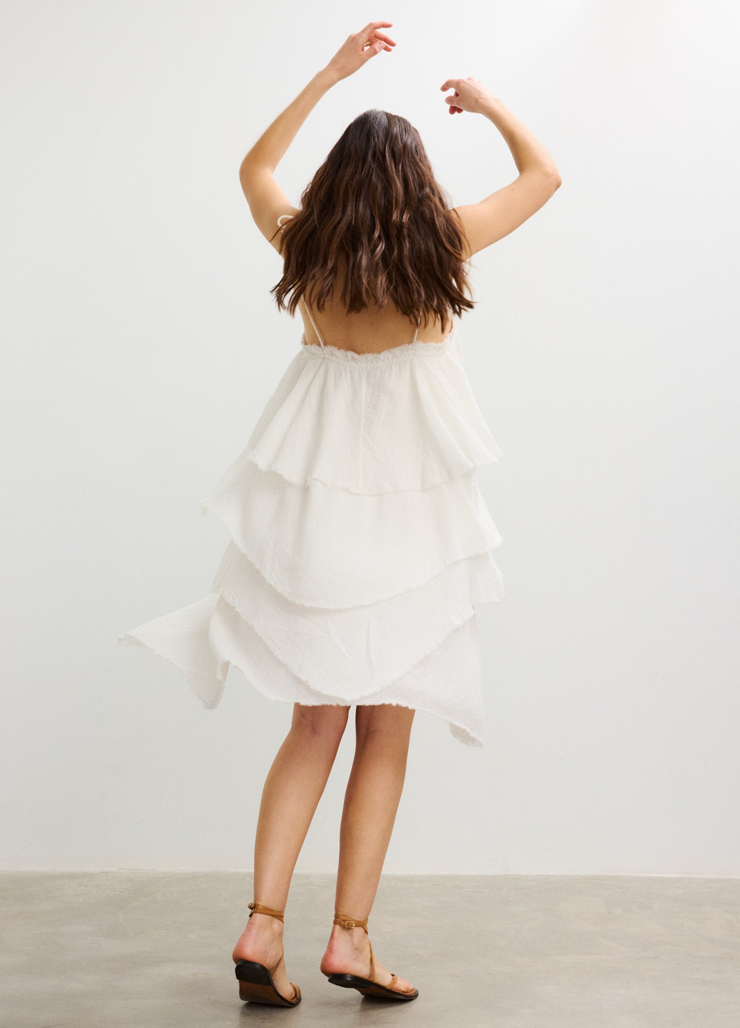 White tiered sleeveless maternity dress with a flowy layered skirt and relaxed fit.