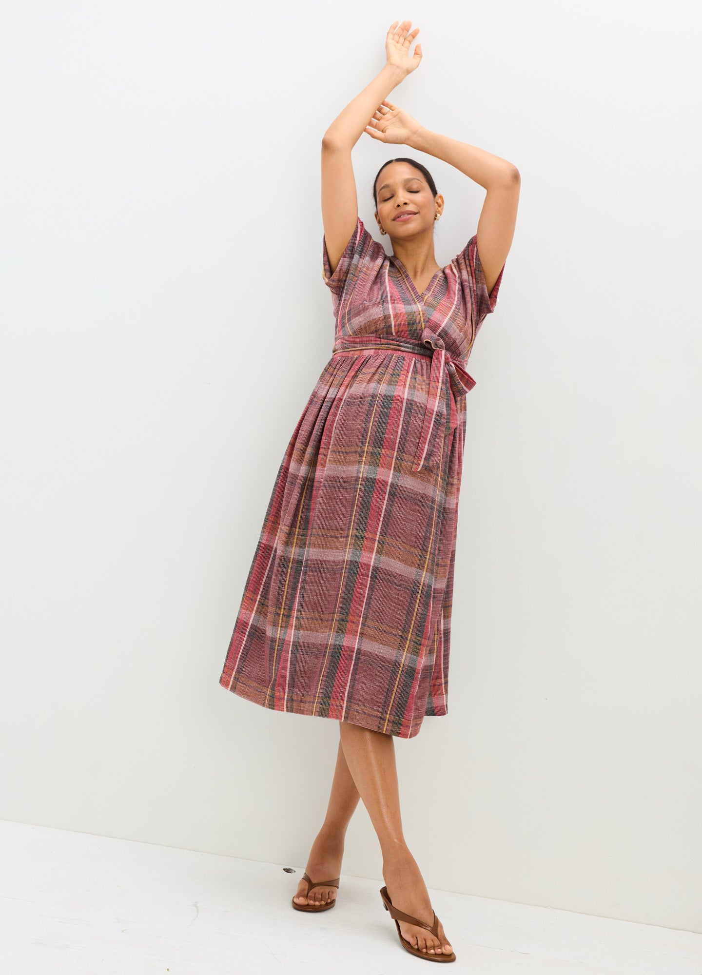 Plaid maternity dress in warm tones with short sleeves and a wrap-style bodice, midi length.