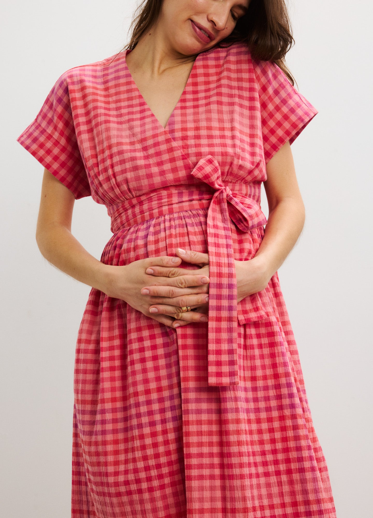 Red and pink checkered maternity dress with V-neck, short sleeves, and waist tie belt.