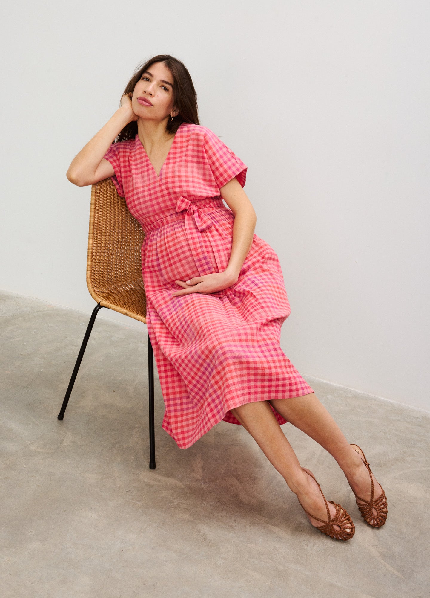 Pink and white checkered maternity dress with short puff sleeves and V-neck, belted waist, midi length.