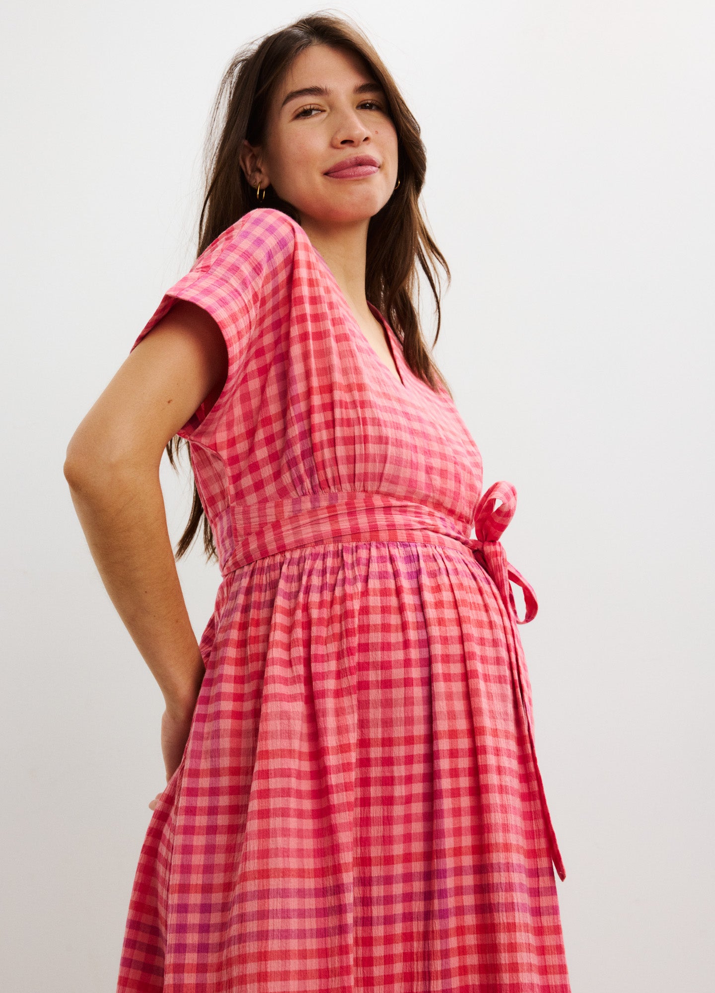 Red and pink plaid maternity dress with short sleeves and tie-waist detail.