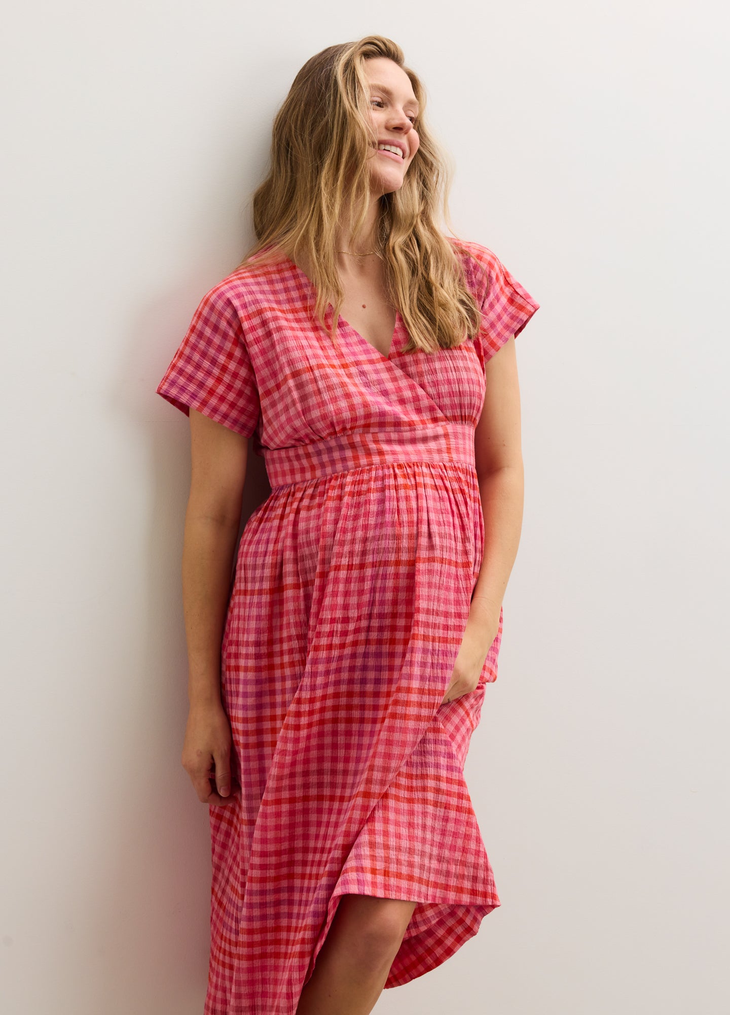 Red and pink plaid maternity dress with short sleeves and a V-neckline, fitted above the baby bump.