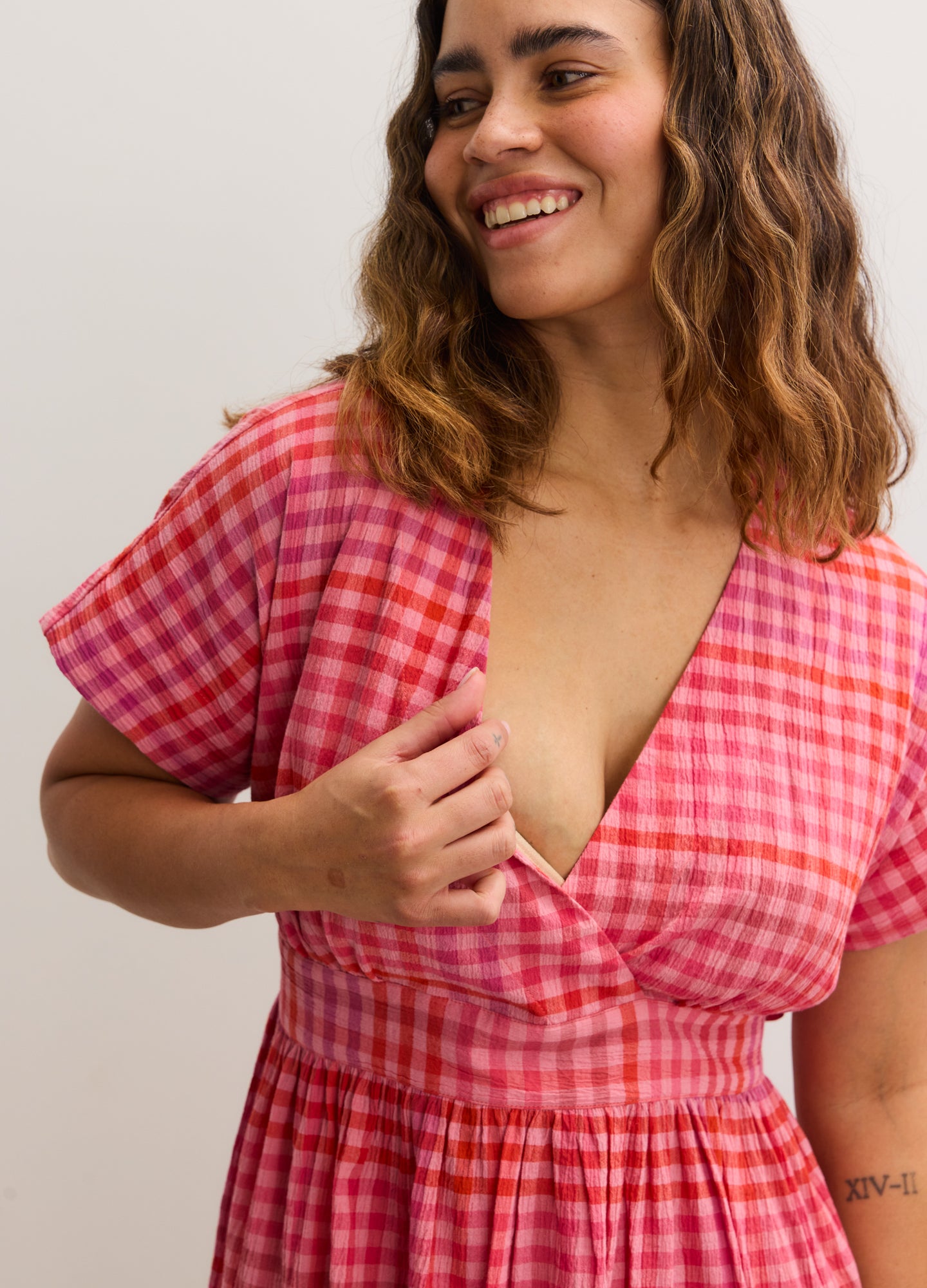 Pink and red gingham maternity dress with short sleeves and a deep V-neckline.