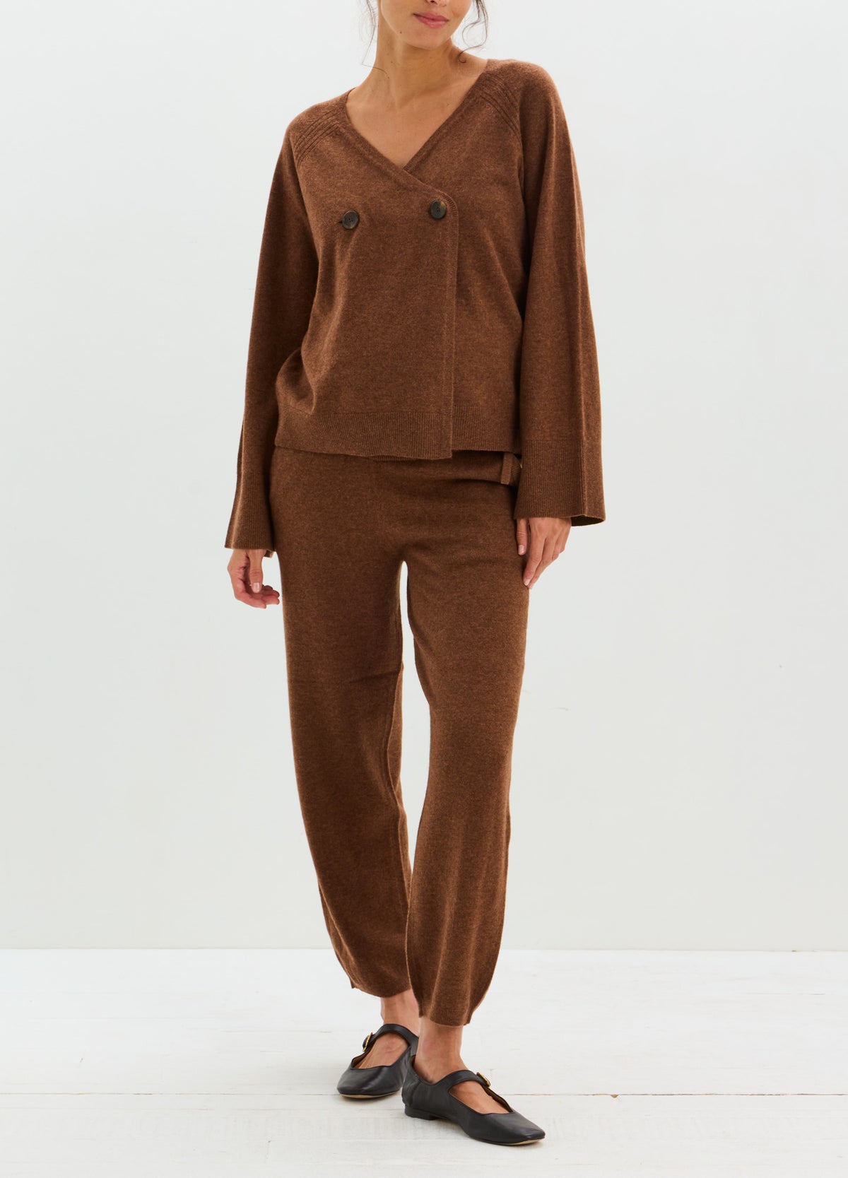 Brown cashmere lounge pants with a relaxed tapered fit and adjustable drawstring waist, styled with a matching sweater.