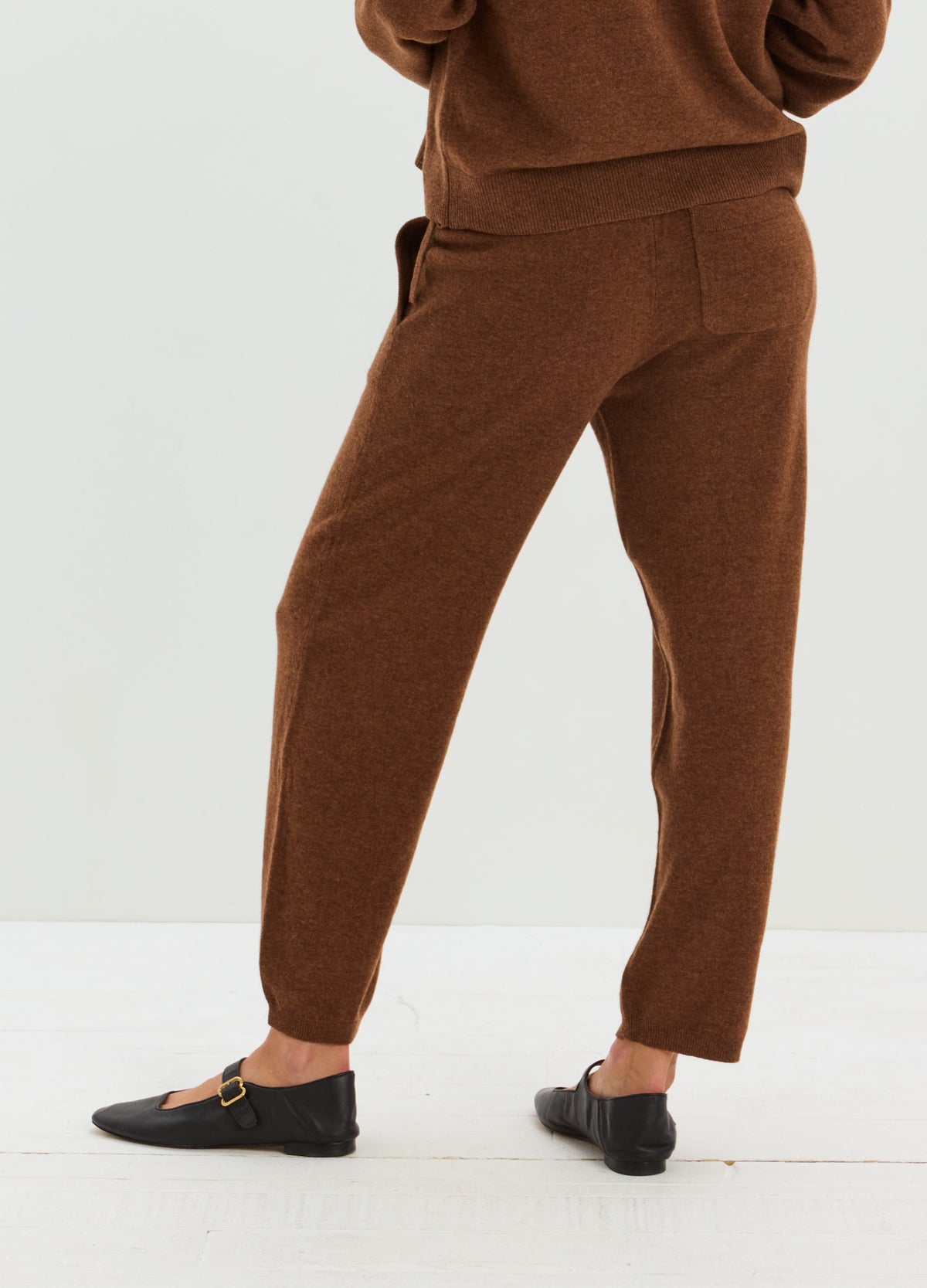 Brown cashmere pants with a relaxed tapered fit and adjustable drawstring waist, paired with black flats.