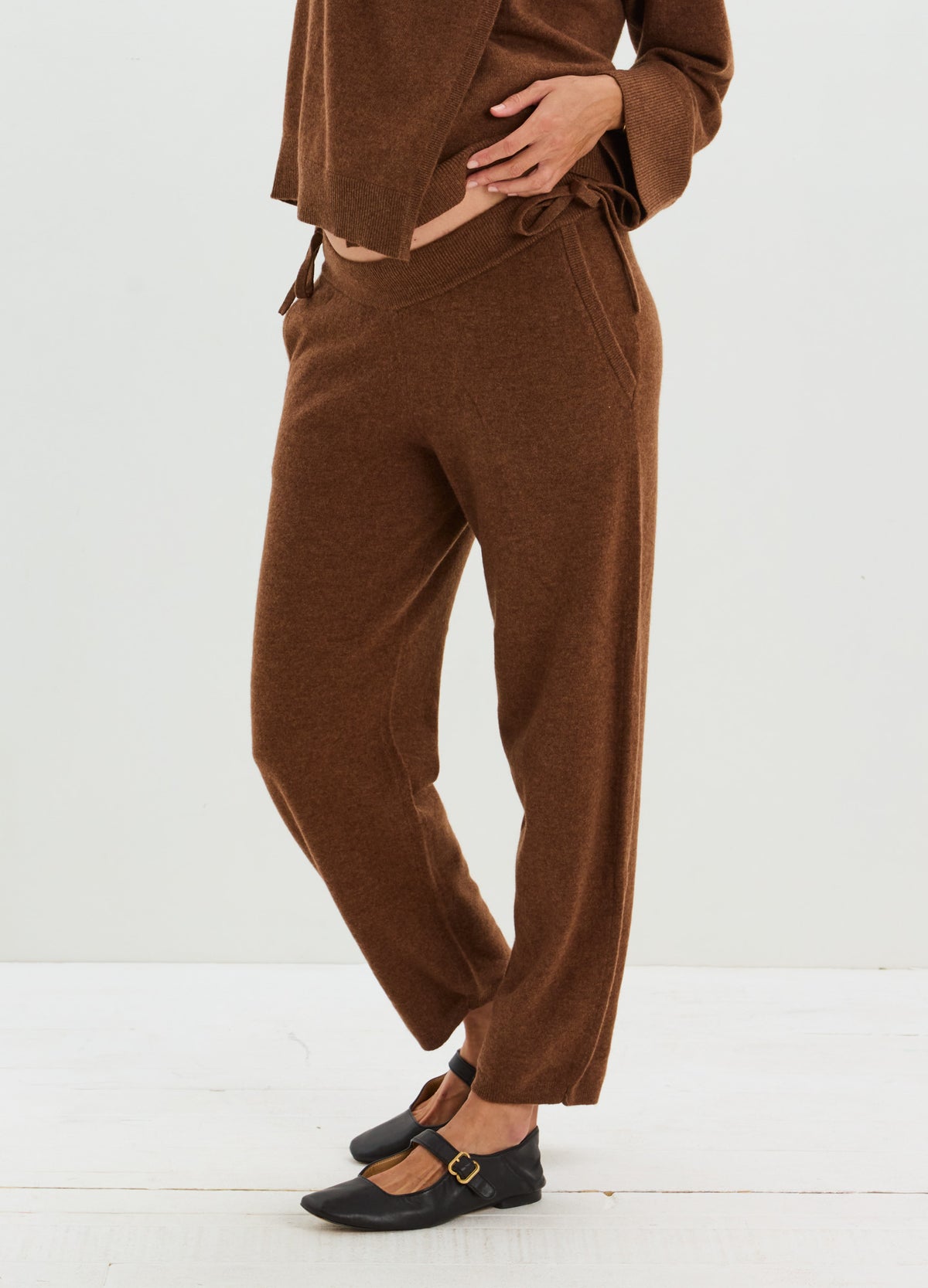 Brown cashmere pants with a relaxed straight-leg fit and adjustable drawstring waist, styled with black flats.