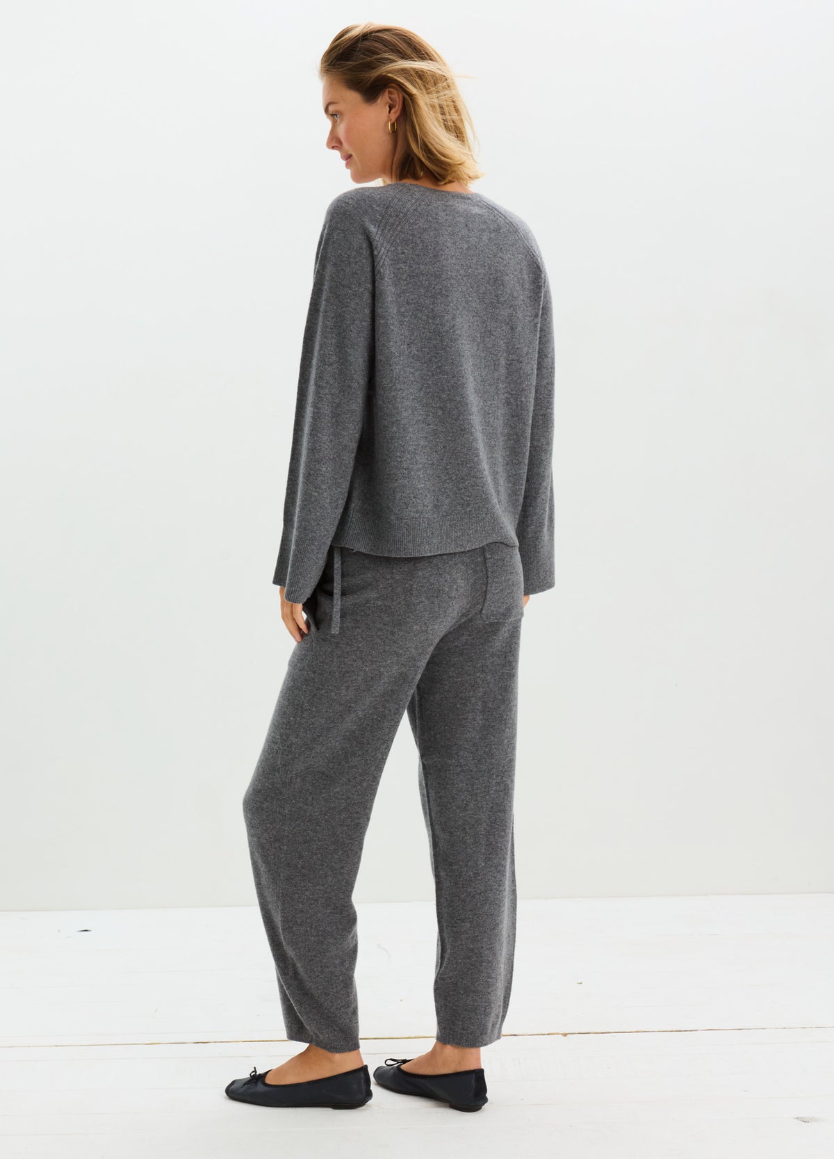 Charcoal gray cashmere lounge pants with a relaxed straight-leg fit and elastic waistband, shown with a matching sweater.