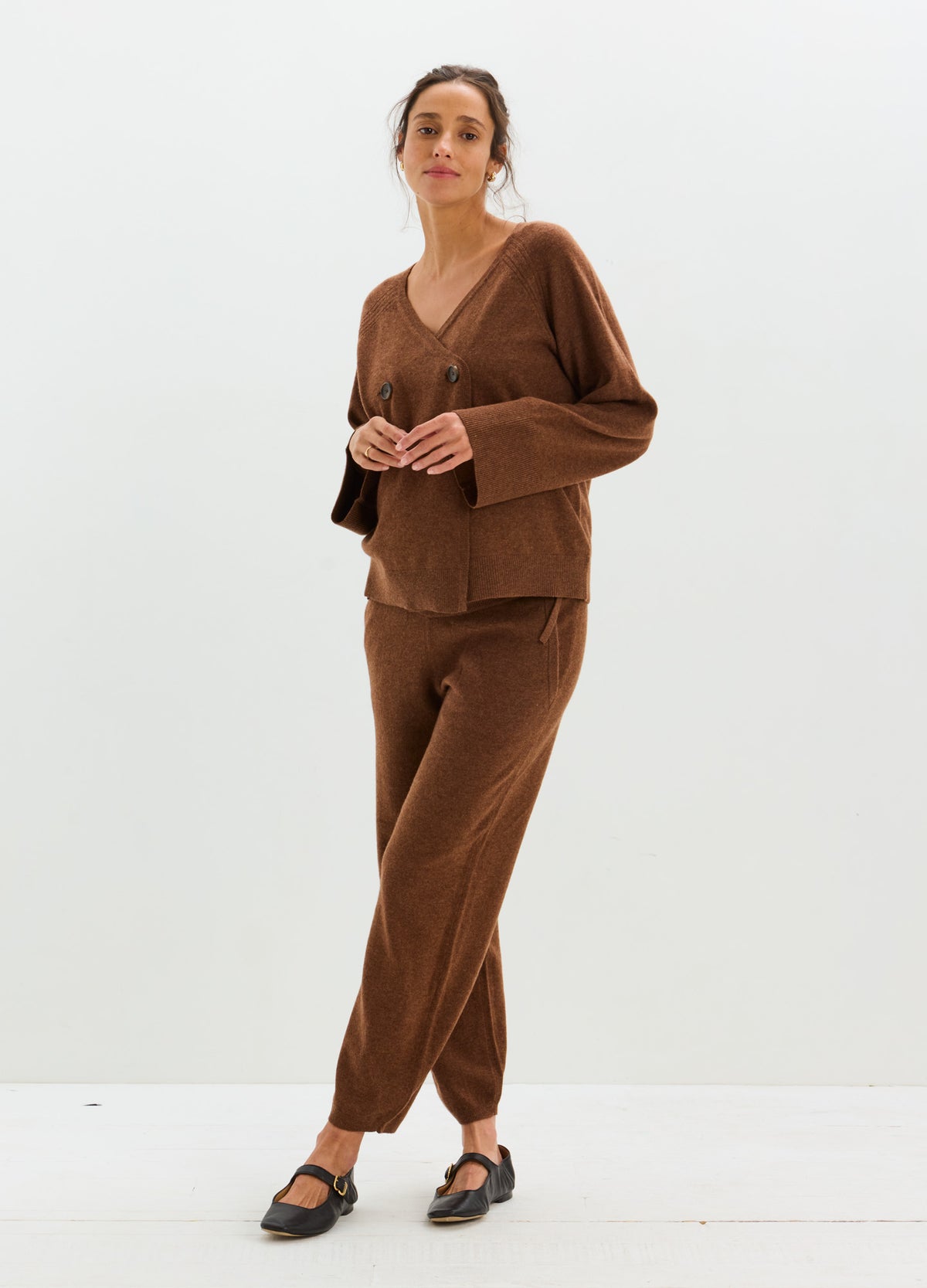 Woman wearing a relaxed brown cashmere cardigan with matching trousers and black sandals.