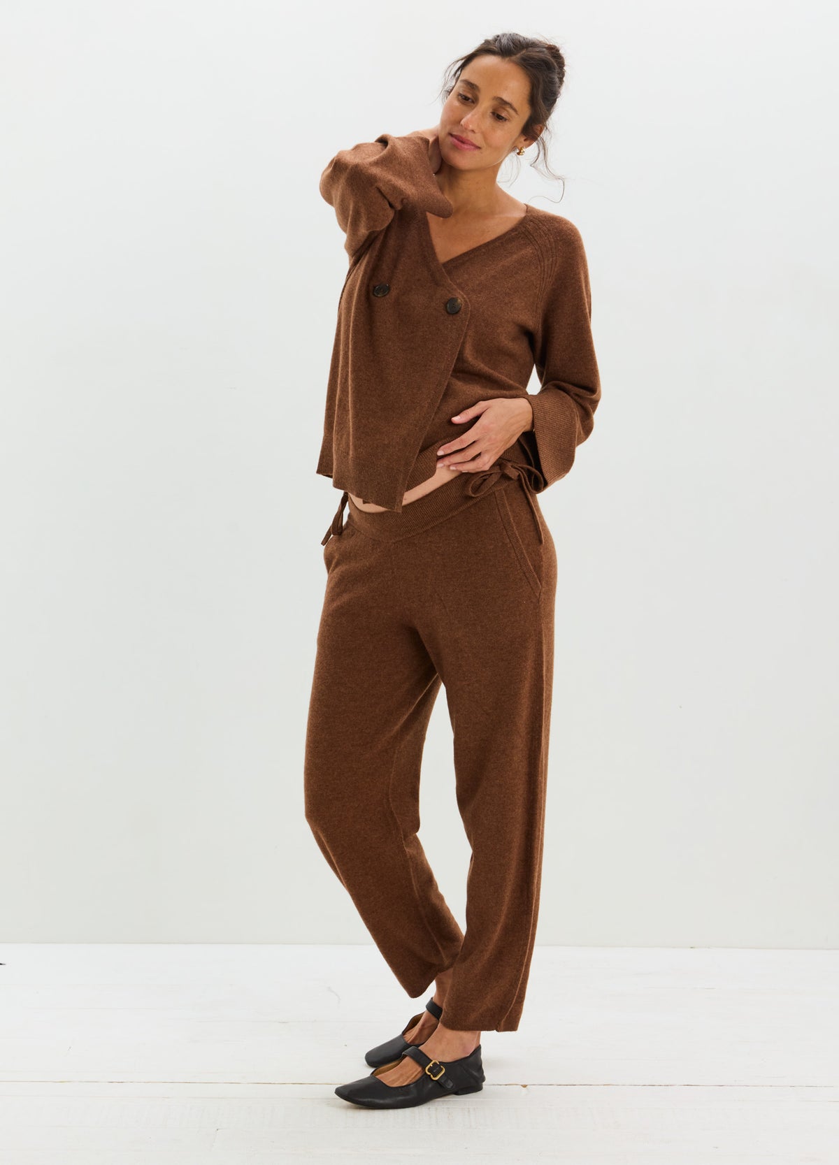 Woman wearing a warm brown cashmere cardigan with a relaxed fit and matching straight-leg pants.