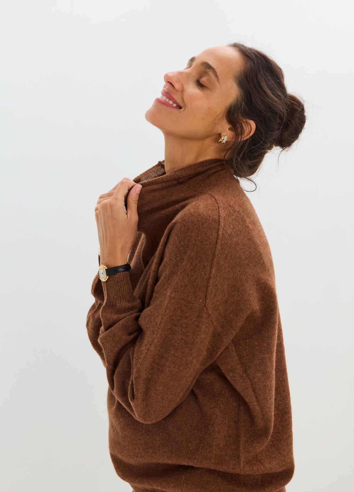 Woman wearing a relaxed-fit chocolate brown cashmere sweater with a soft knit texture and ribbed cuffs.
