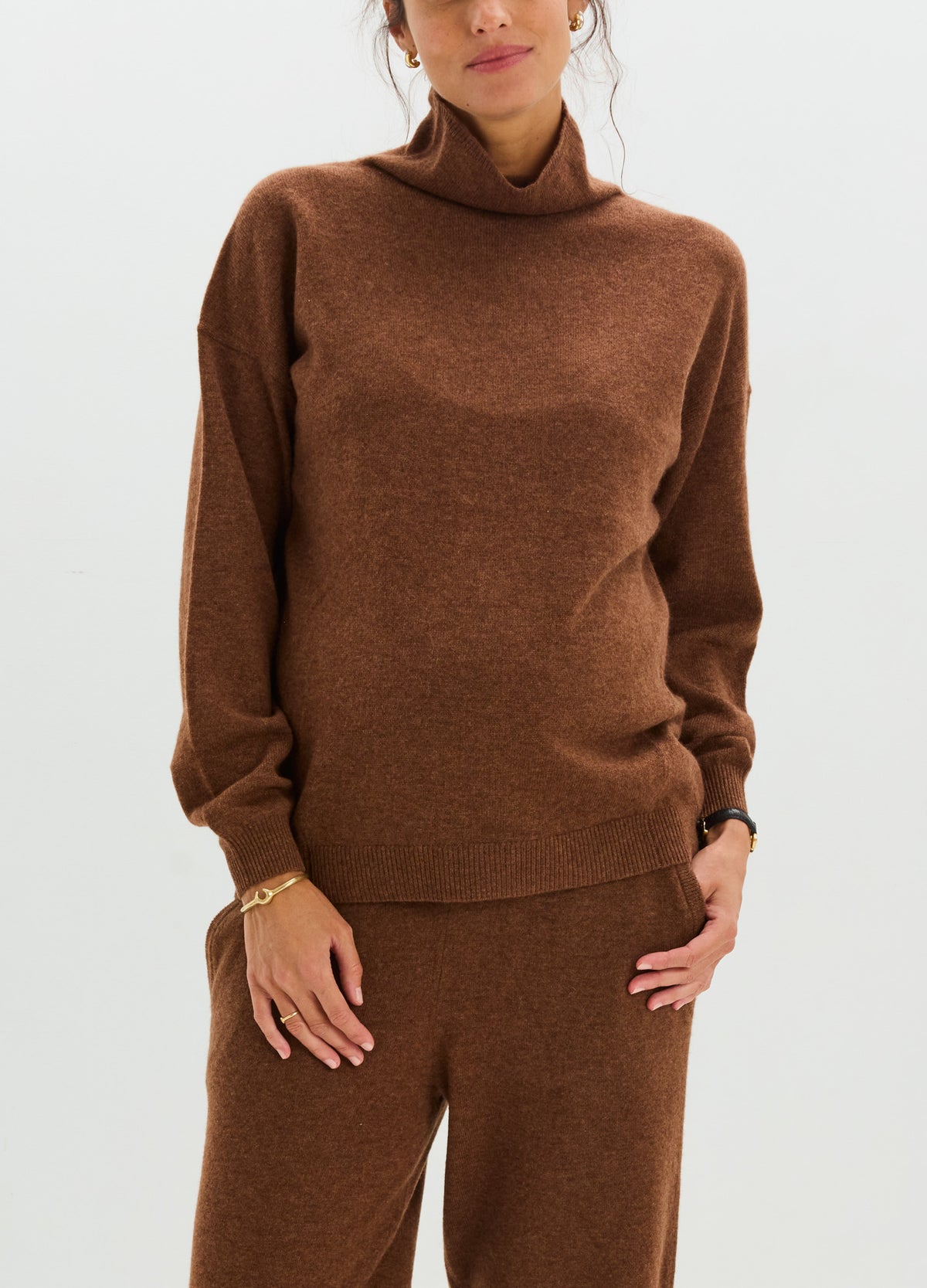Brown cashmere sweater with a relaxed fit, high folded neckline, and ribbed cuffs and hem, styled with matching pants.