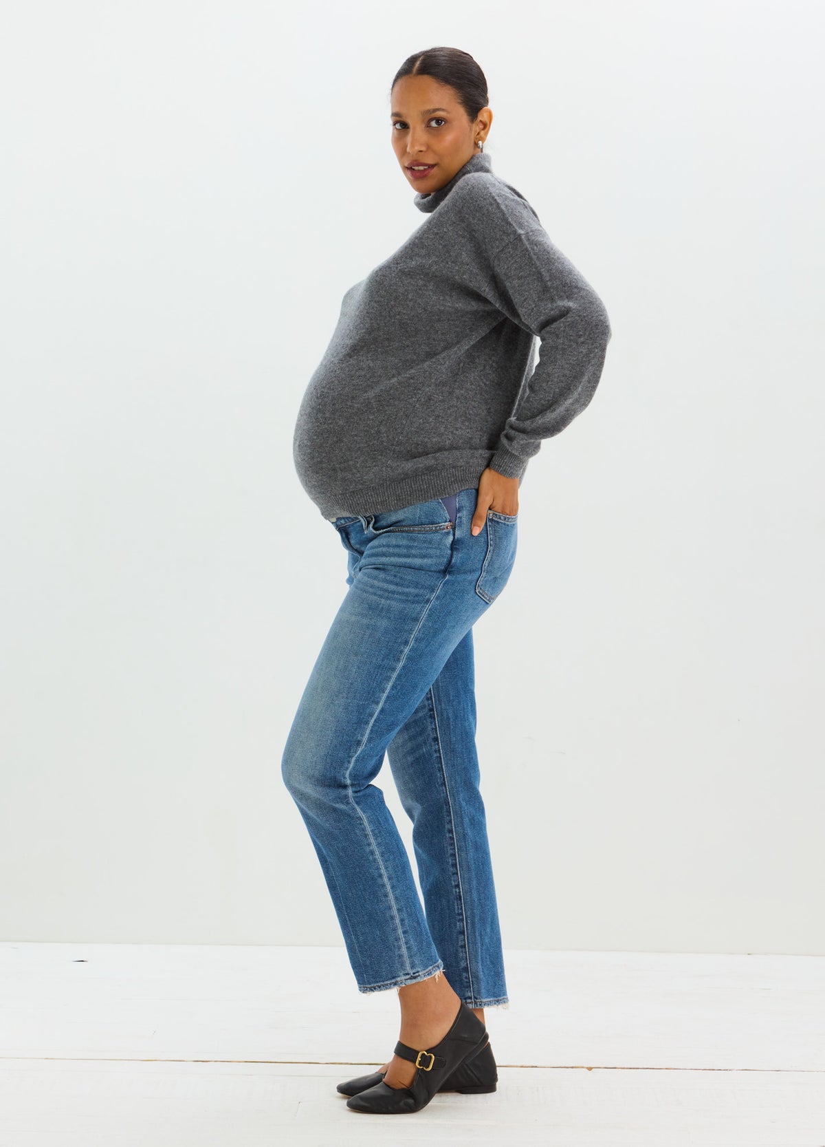 Charcoal gray cashmere sweater with a relaxed fit and ribbed cuffs, paired with blue jeans.