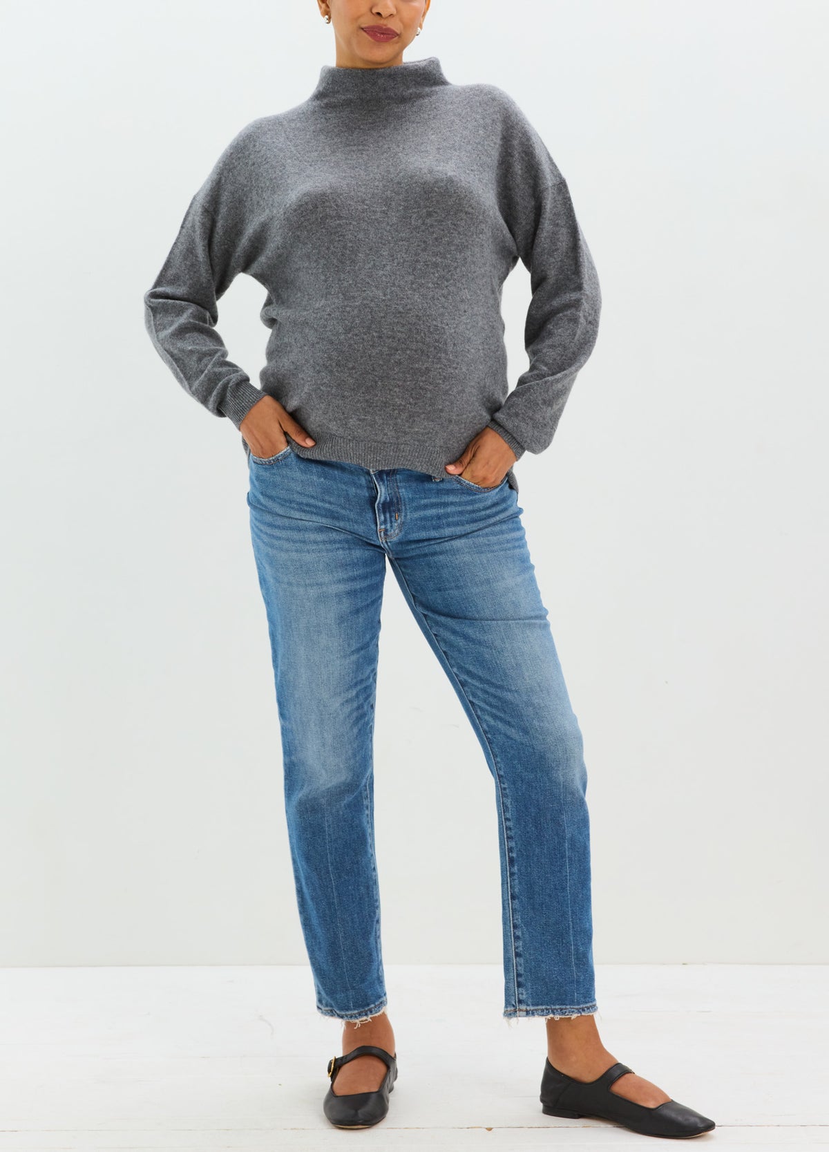 Charcoal gray cashmere sweater with a relaxed fit, high neckline, and long sleeves, styled with blue jeans.