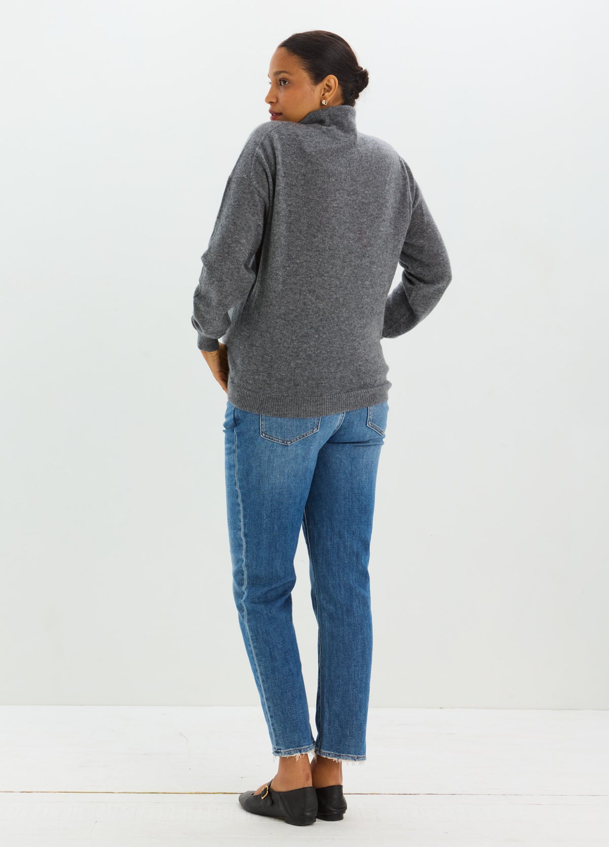 Gray cashmere sweater with a relaxed fit and high neckline, styled with blue jeans and black flats.