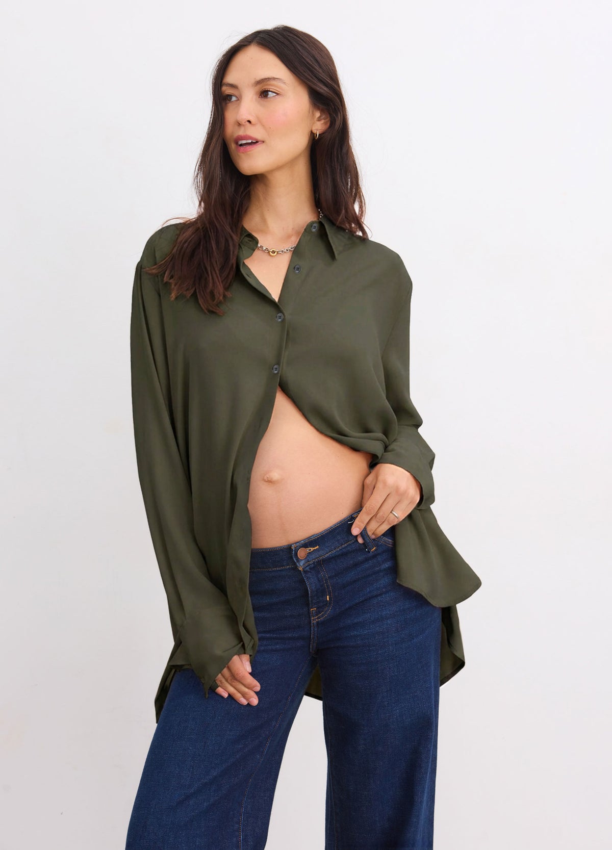 Olive green drapey button-down with a pointed collar, long sleeves, and flared cuffs, worn with dark blue jeans.