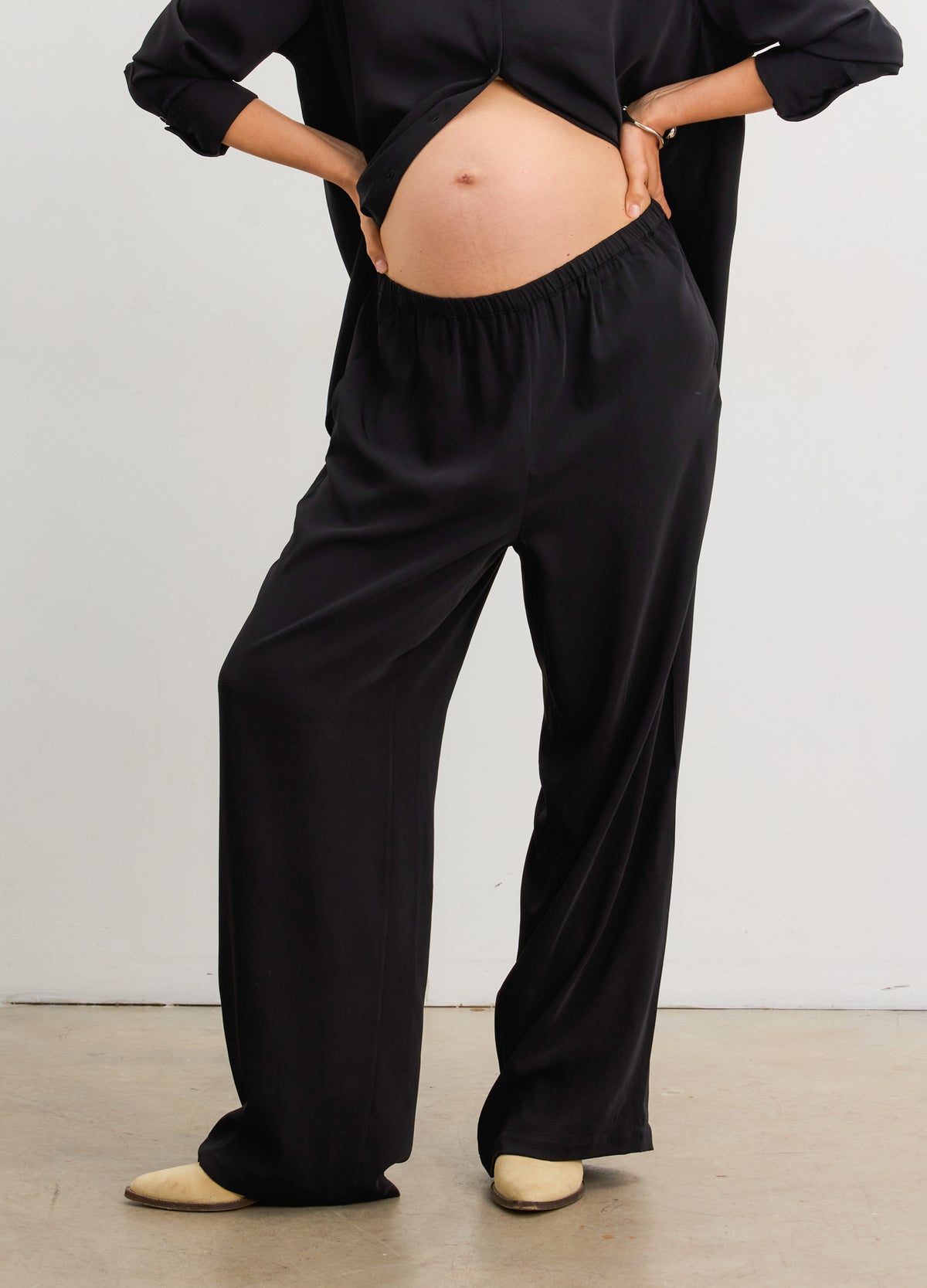Black drapey maternity pull-on pants with soft elastic waistband, worn by pregnant model.
