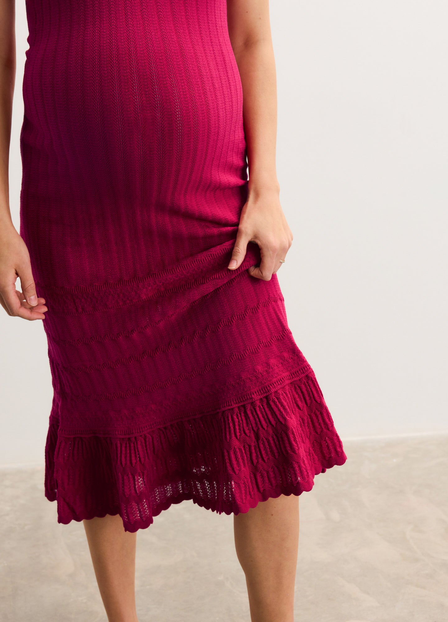 Deep magenta ribbed maternity dress with fitted silhouette and ruffled hem.