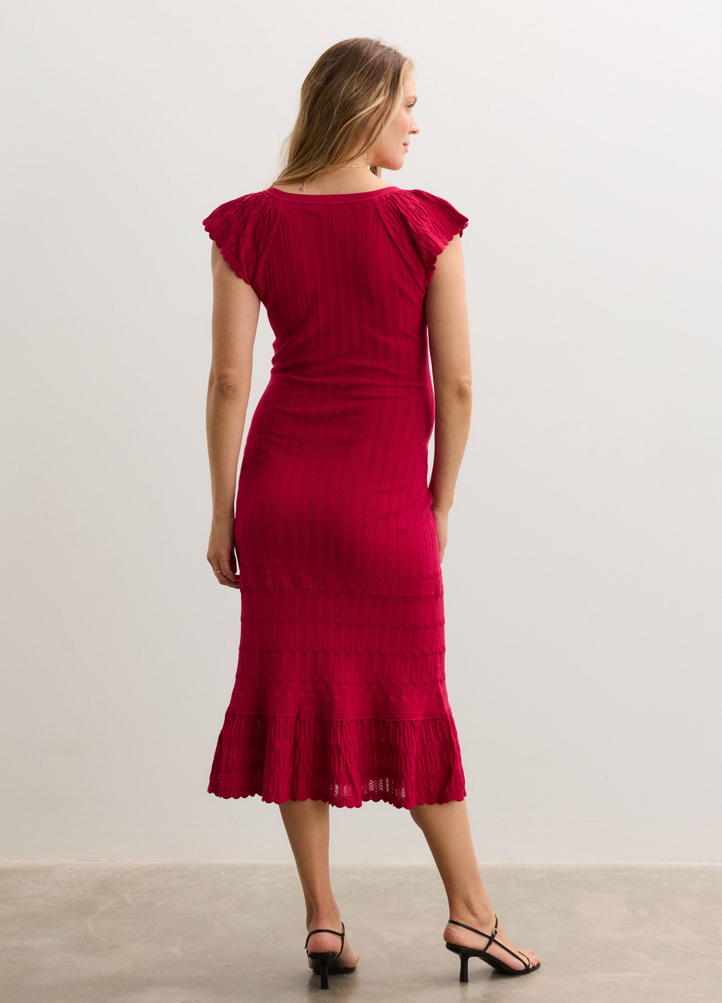 Sleeveless deep red midi maternity dress with fitted bodice and flared hem detailing.