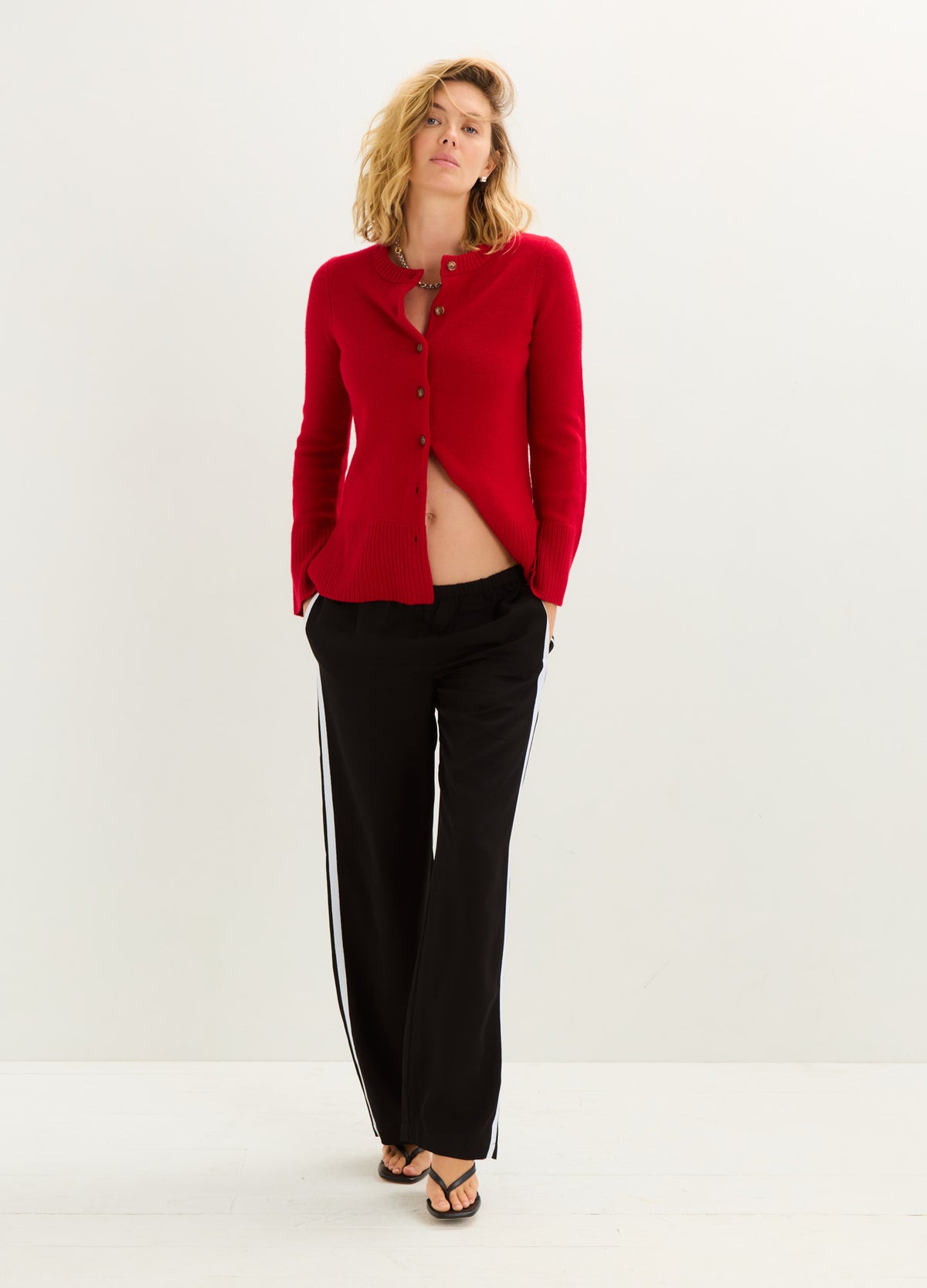 Red knitted maternity cardigan with contour fit and button closure, styled open at the waist.