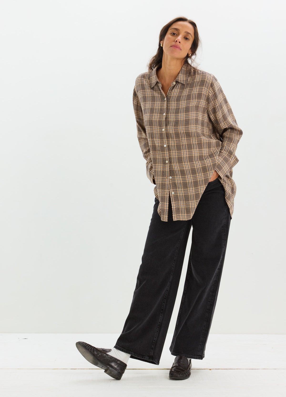 Loose-fit brown plaid maternity buttondown shirt with long sleeves and a collar paired with wide-leg black pants and black.