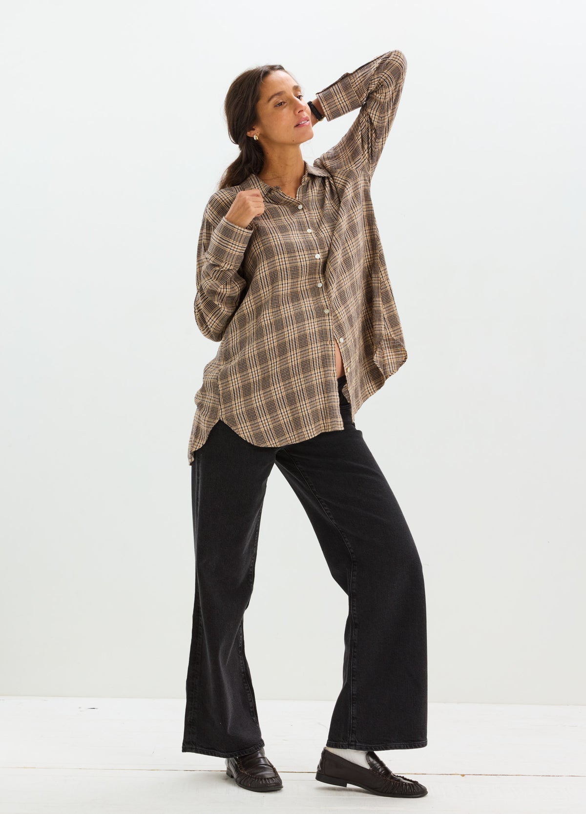 Taupe and brown plaid maternity button-down shirt with long sleeves and rounded hem, paired with black wide-leg pants.