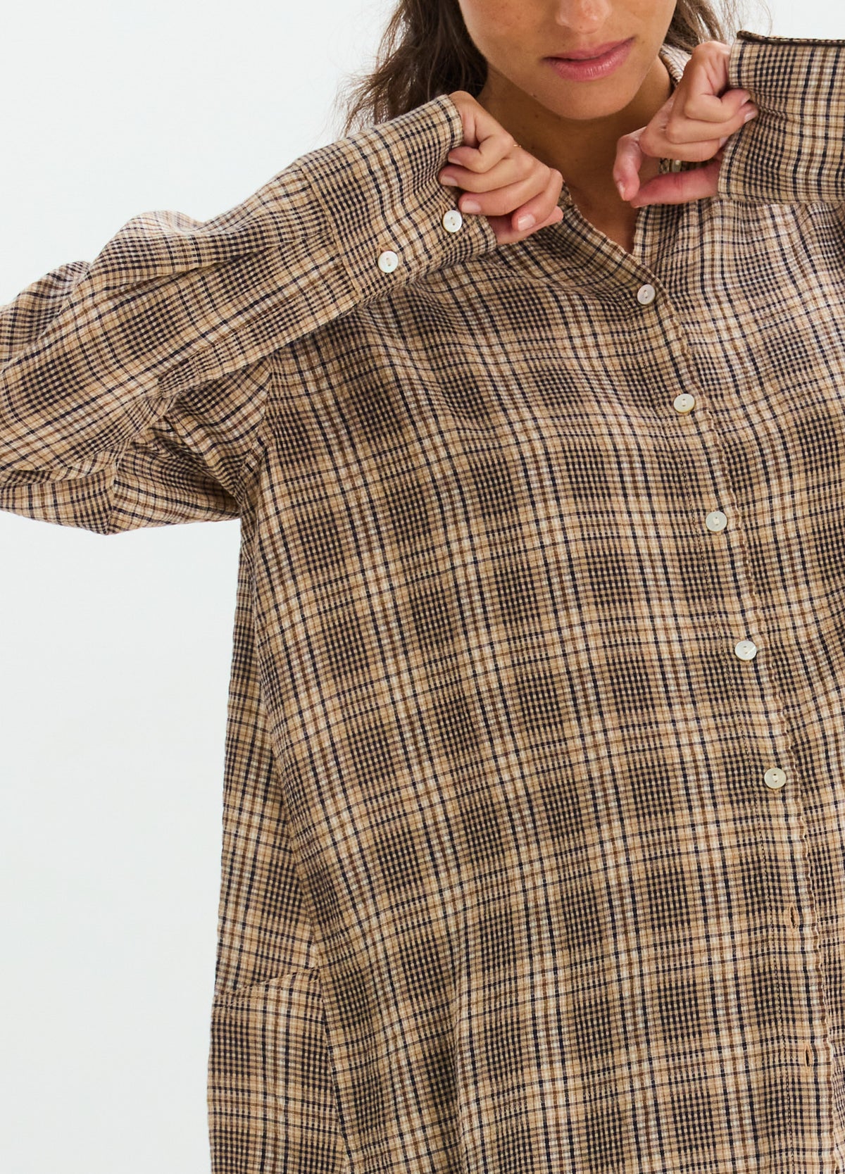 Brown and beige plaid maternity button-down shirt with long sleeves and white buttons.
