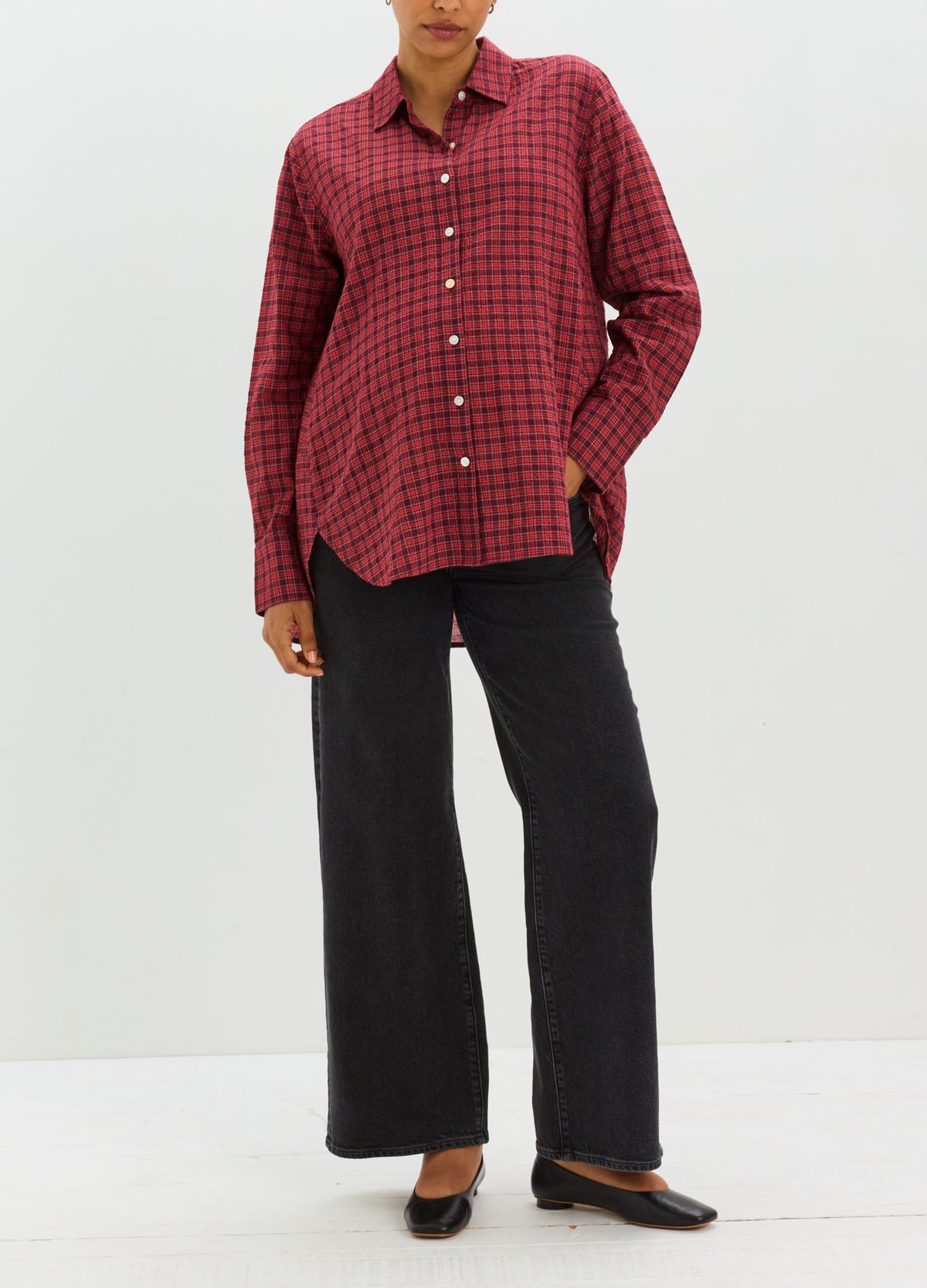 Red and black checkered long-sleeve buttondown shirt with relaxed fit, styled for maternity, paired with black wide-leg.