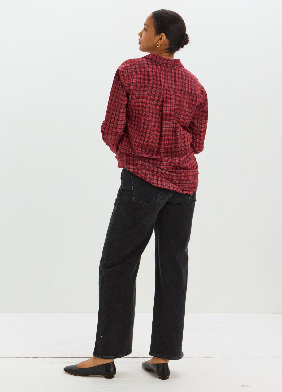 Red and black plaid maternity buttondown shirt with long sleeves and relaxed fit paired with black wide-leg pants.