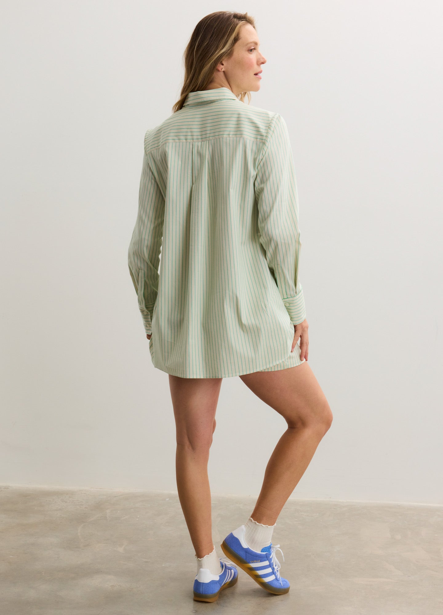 Light green oversized maternity button-down shirt with long sleeves and curved hem, worn by a pregnant model.