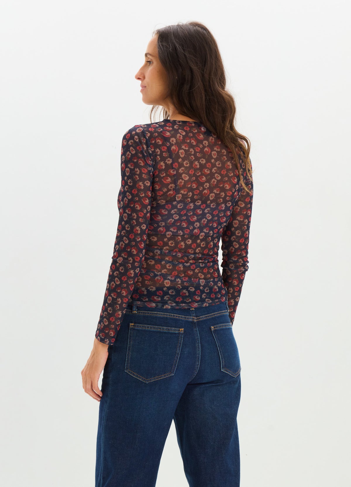 Long-sleeve fitted maternity top with a dark floral print, paired with high-waisted blue jeans.