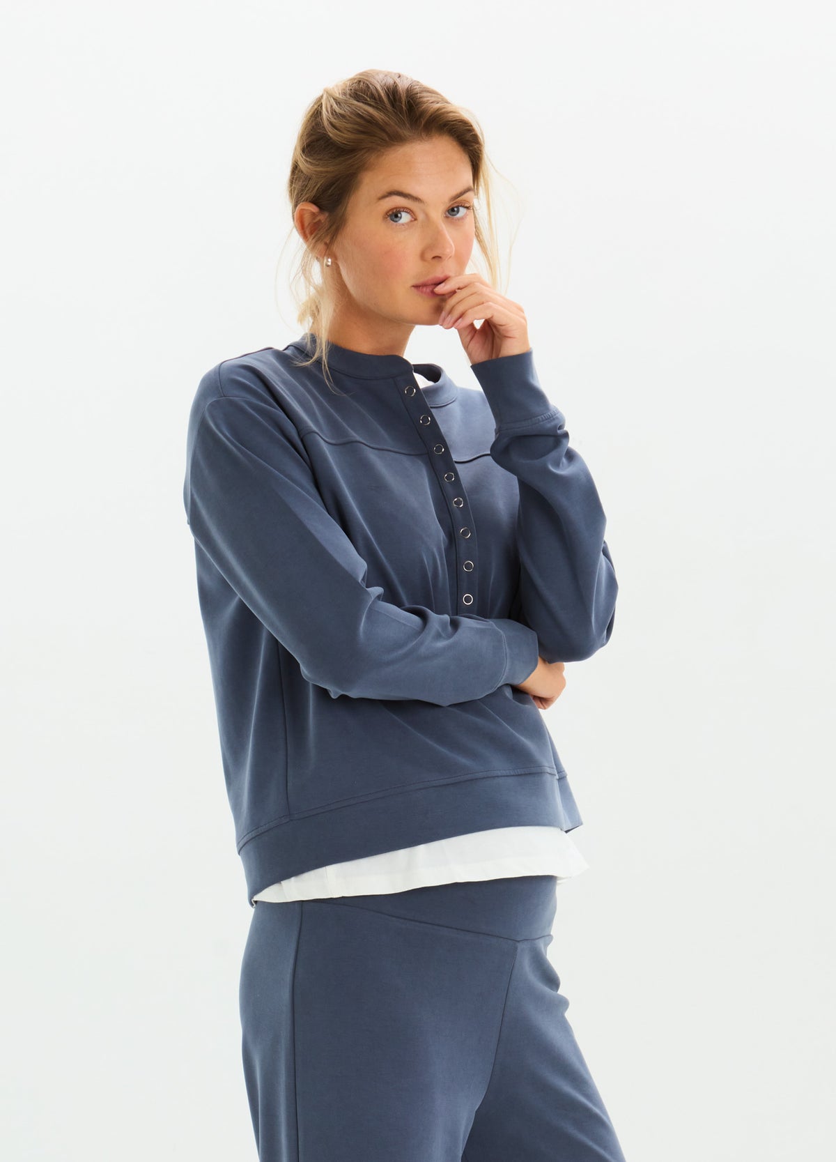 Maternity pullover in soft navy fabric with relaxed fit, layered over white top, modeled by pregnant woman.