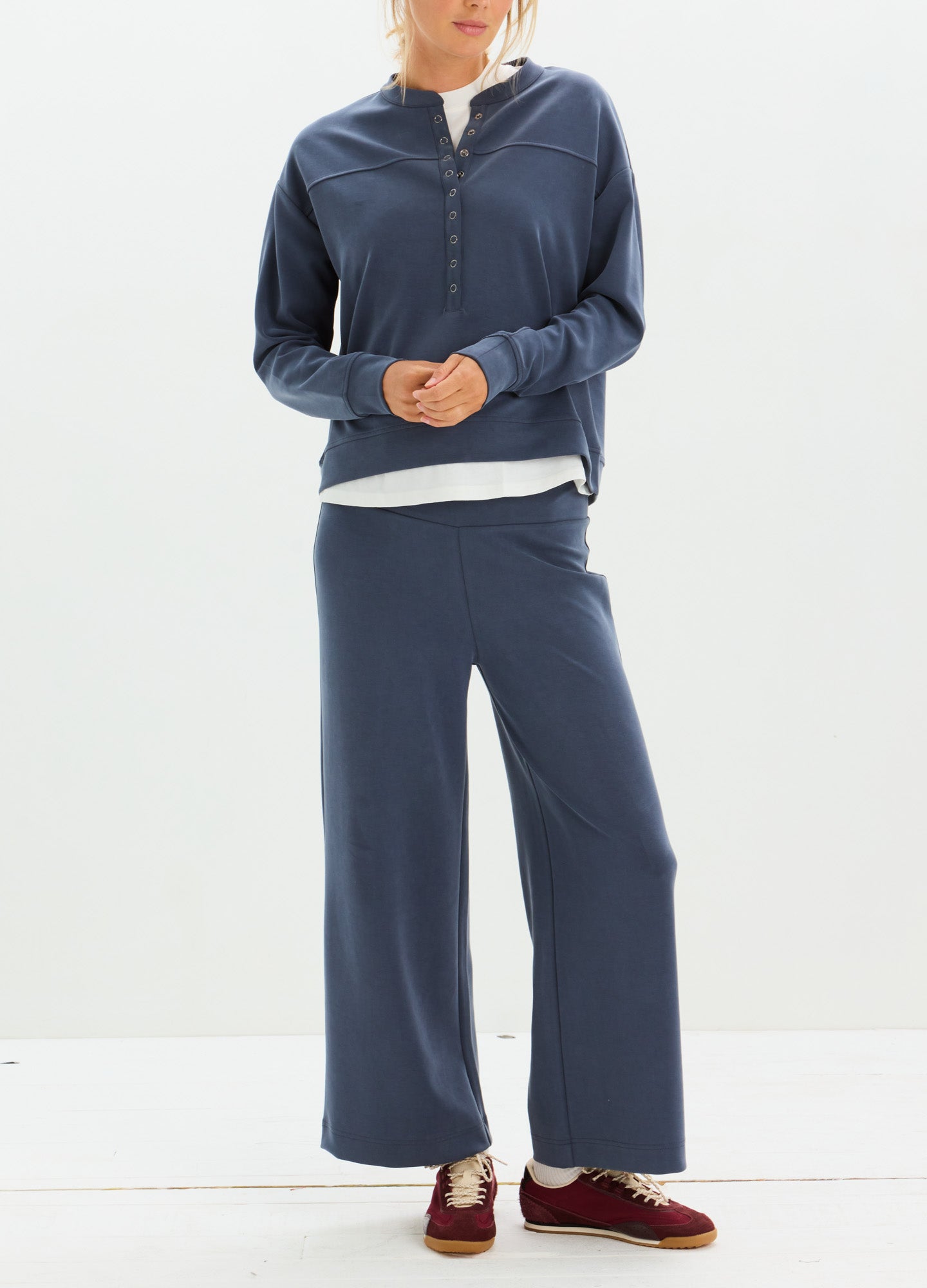 Navy blue soft knit maternity pants with wide legs, paired with a matching zip-up jacket and burgundy loafers.