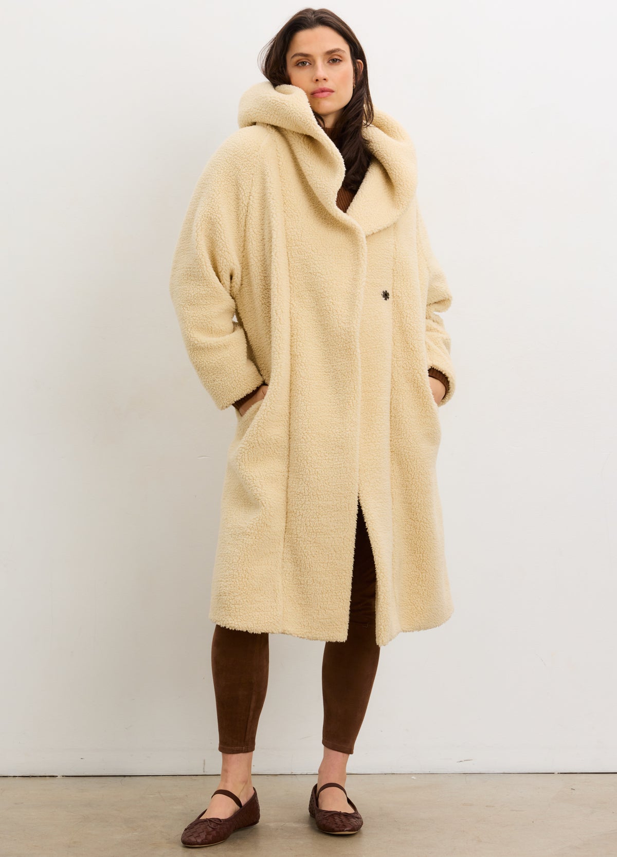 Cream-colored shearling cocoon coat with oversized hood and relaxed fit, styled for maternity wear.