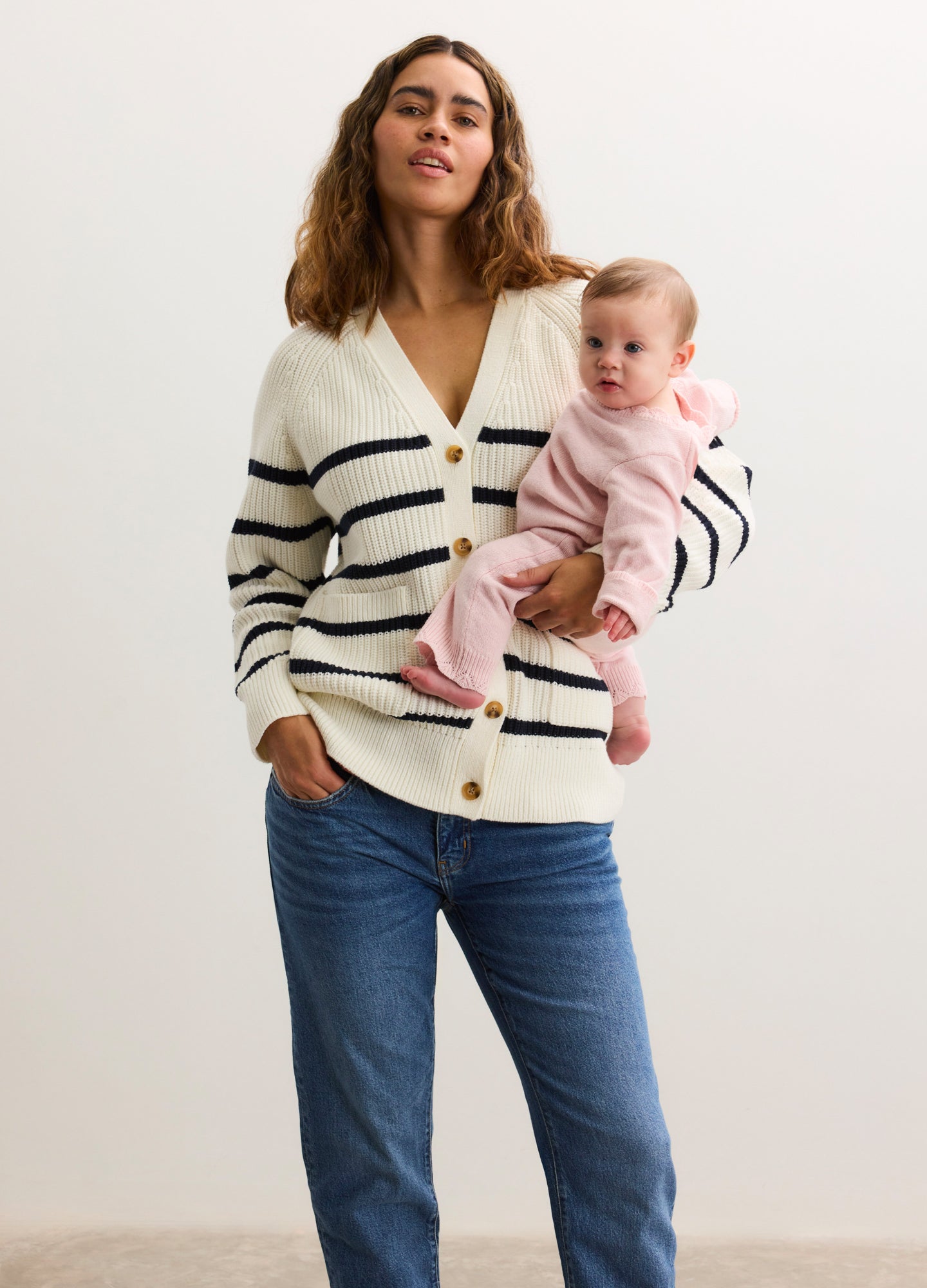 Cream cardigan with black horizontal stripes, V-neck, button front, worn over maternity jeans.