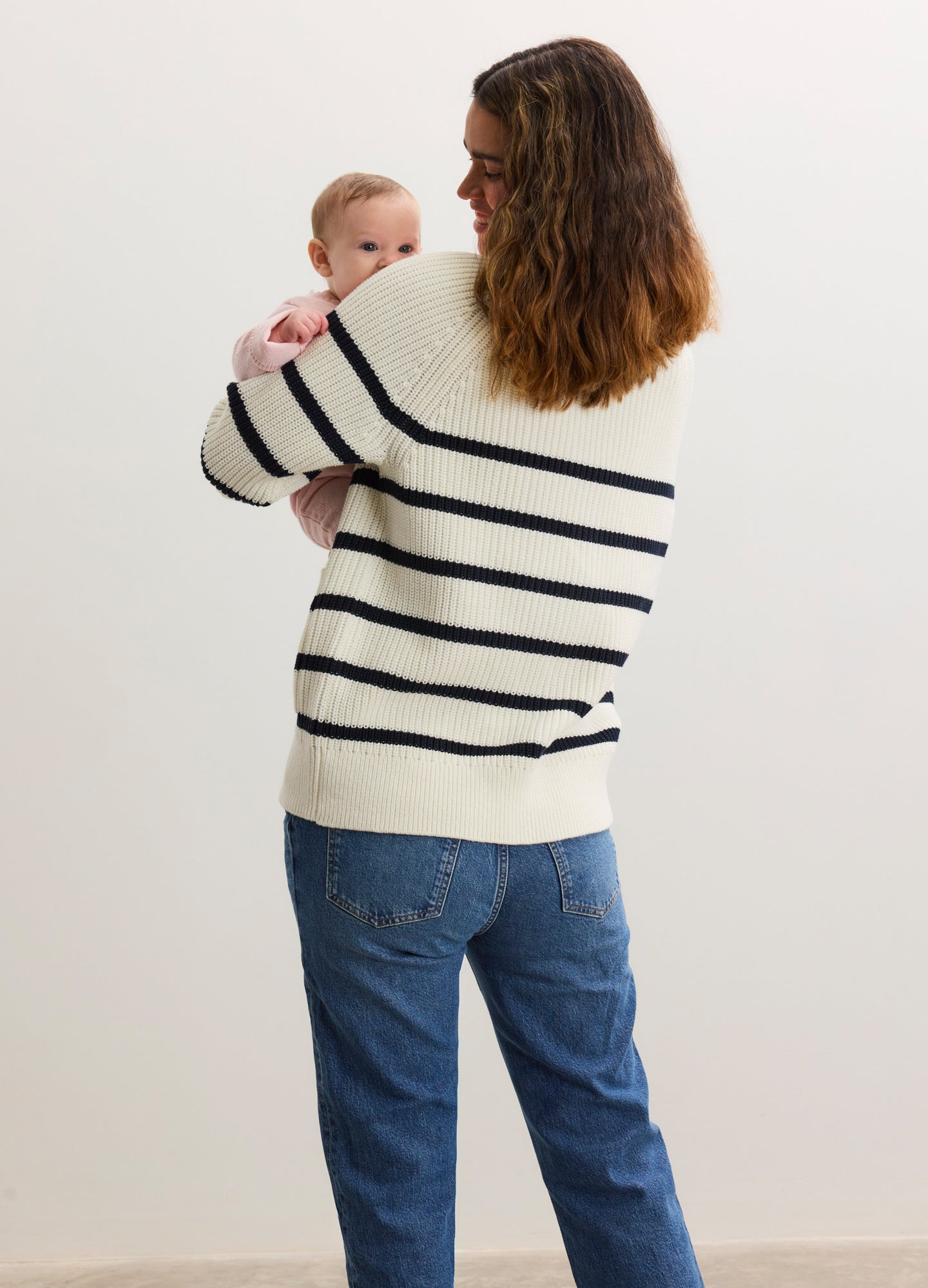 Cream and navy striped knitted cardigan with a relaxed fit, worn by a pregnant woman holding a baby.