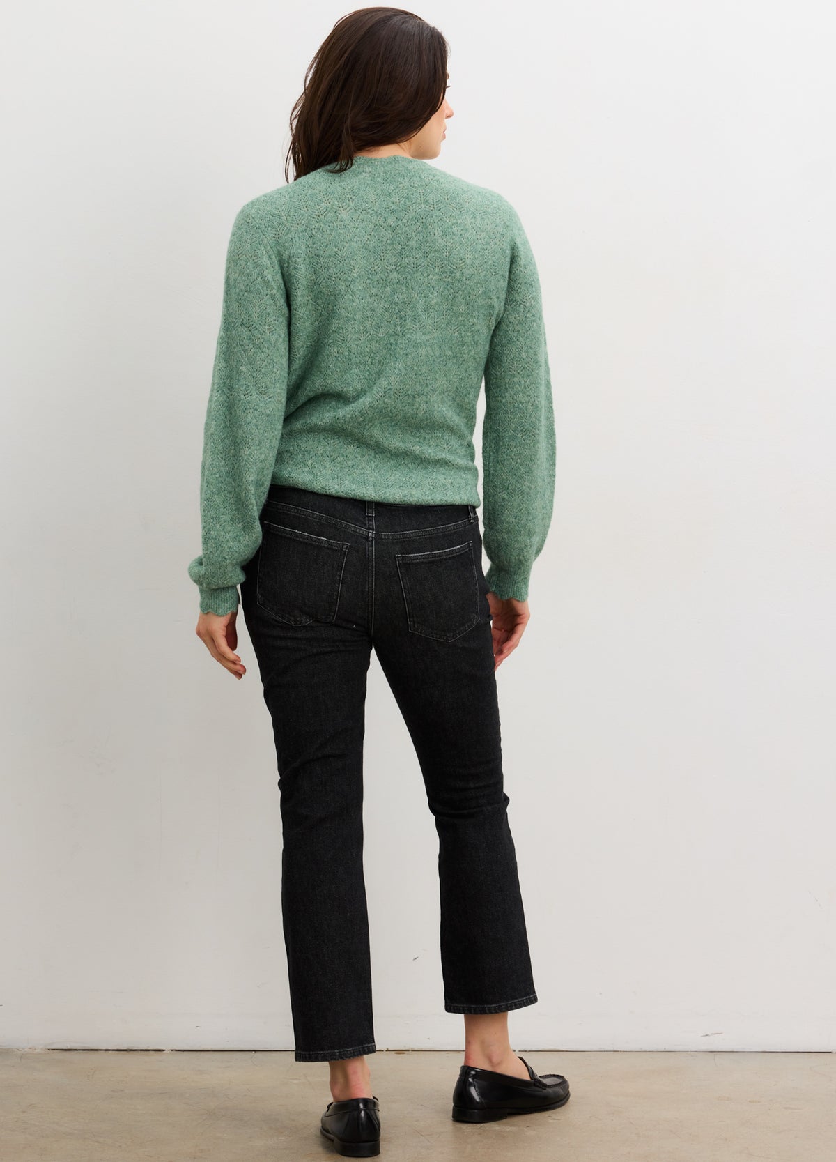 Soft green knit sweater with pointelle detailing and relaxed fit, paired with black cropped jeans and black flats.