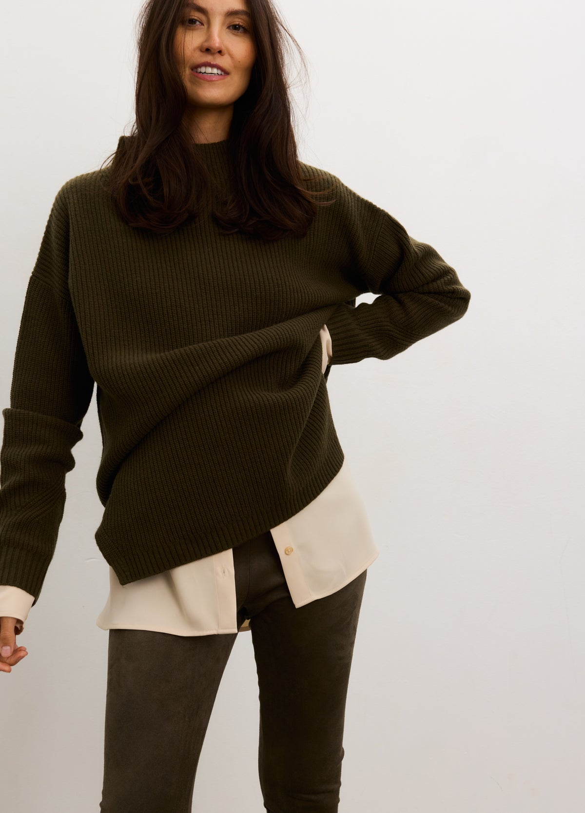 Olive green maternity turtleneck sweater with relaxed fit and side slits worn by pregnant model.