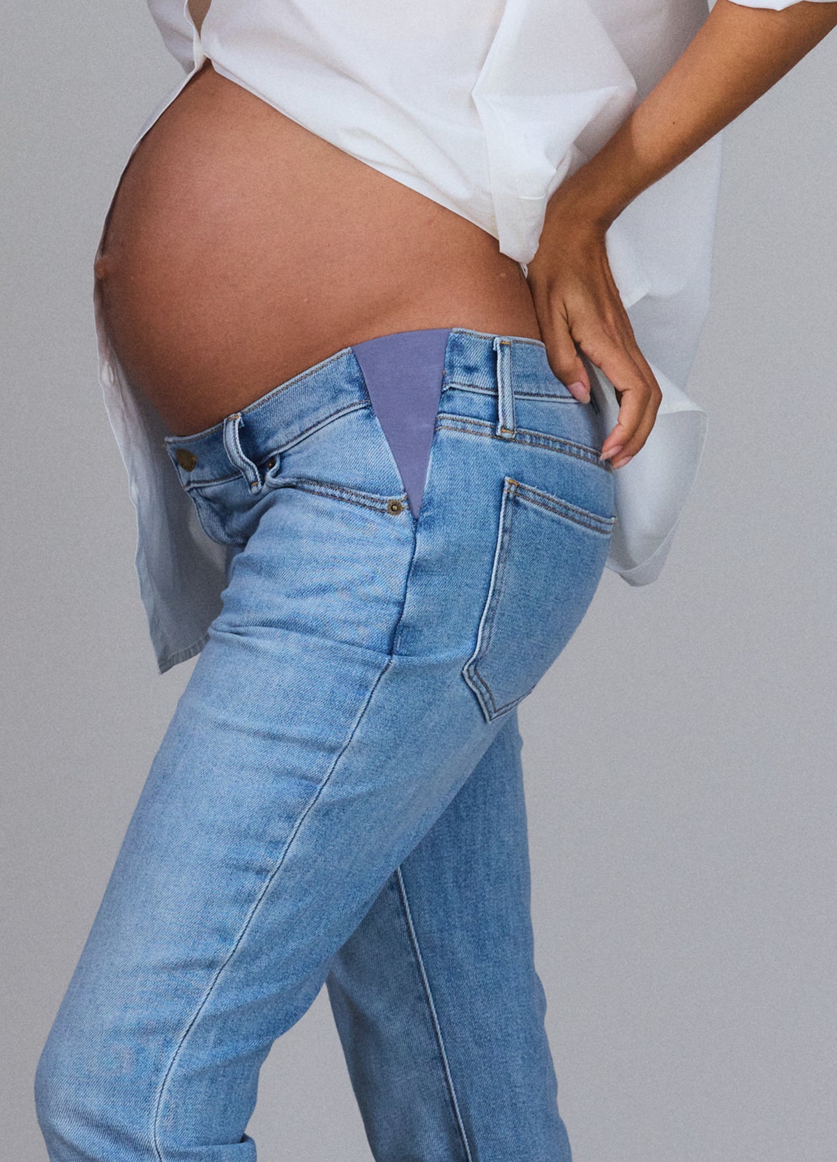 Light wash maternity jeans with stretchy panel designed for pregnant belly comfort.