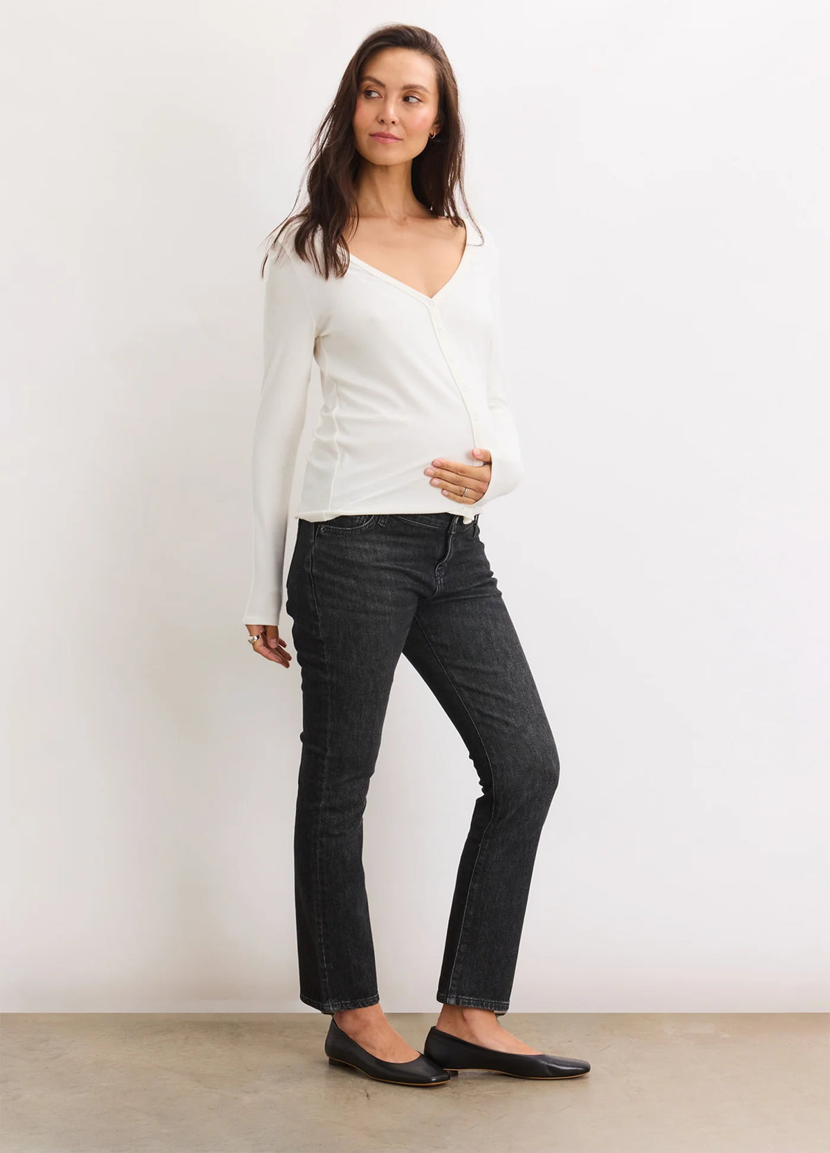 Pregnant woman wearing washed black maternity crop jeans with a supportive belly band and straight leg fit.