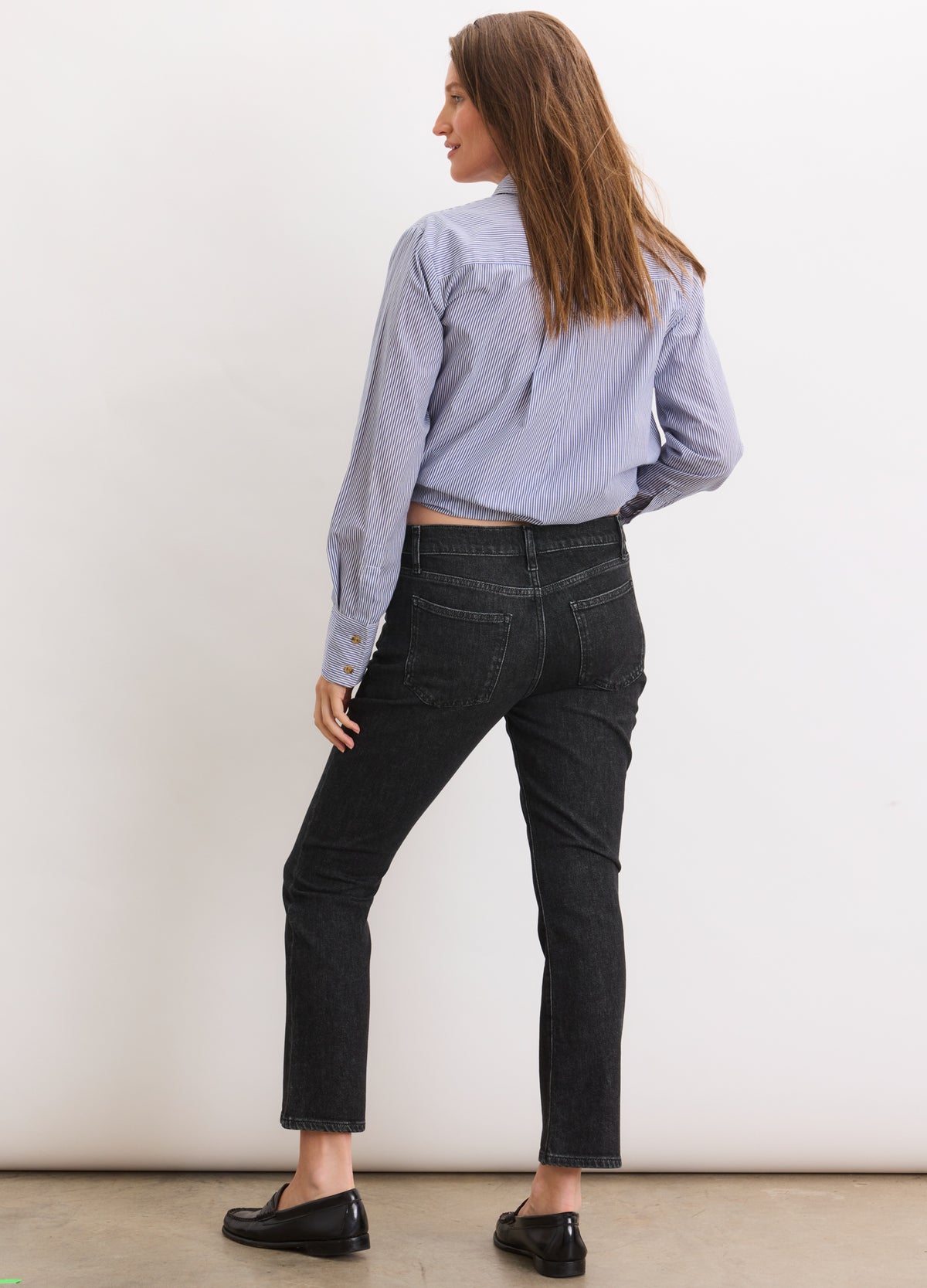 Black cropped maternity jeans with a slim fit and stretch fabric, worn by a pregnant model.