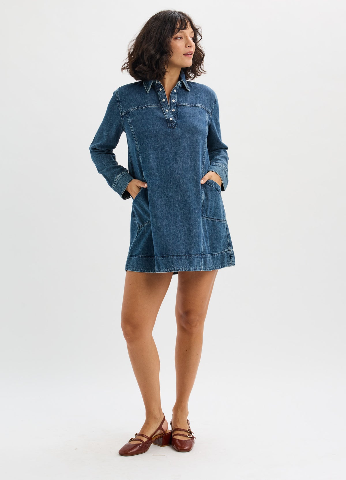 Blue denim mini dress with long sleeves, collar, button placket, and a relaxed fit for maternity wear.