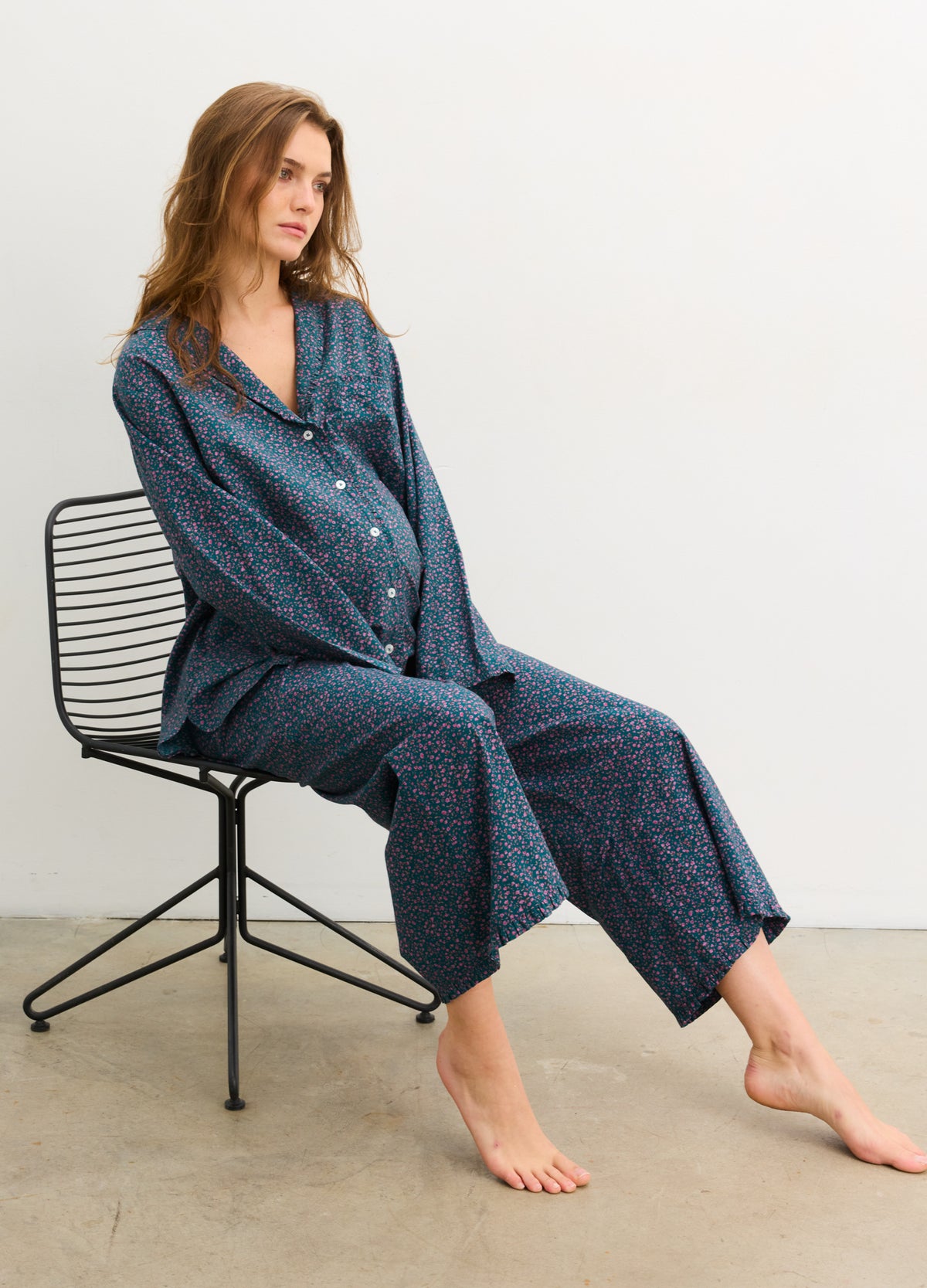 Dark blue maternity pajama pants with ruffle hem, worn by pregnant model sitting on black chair.