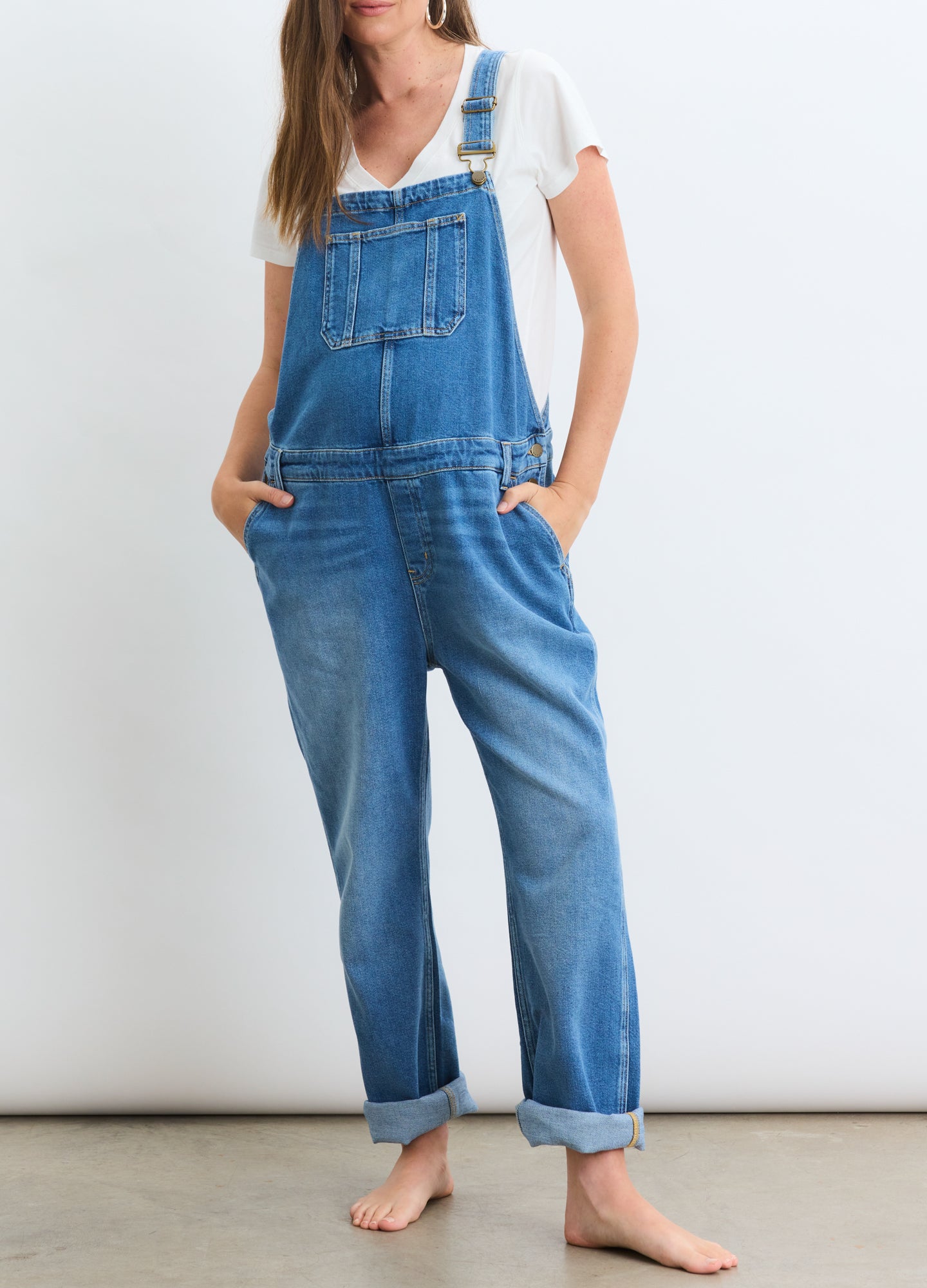 Blue denim maternity overall with adjustable straps, front bib pocket, and relaxed straight leg fit.