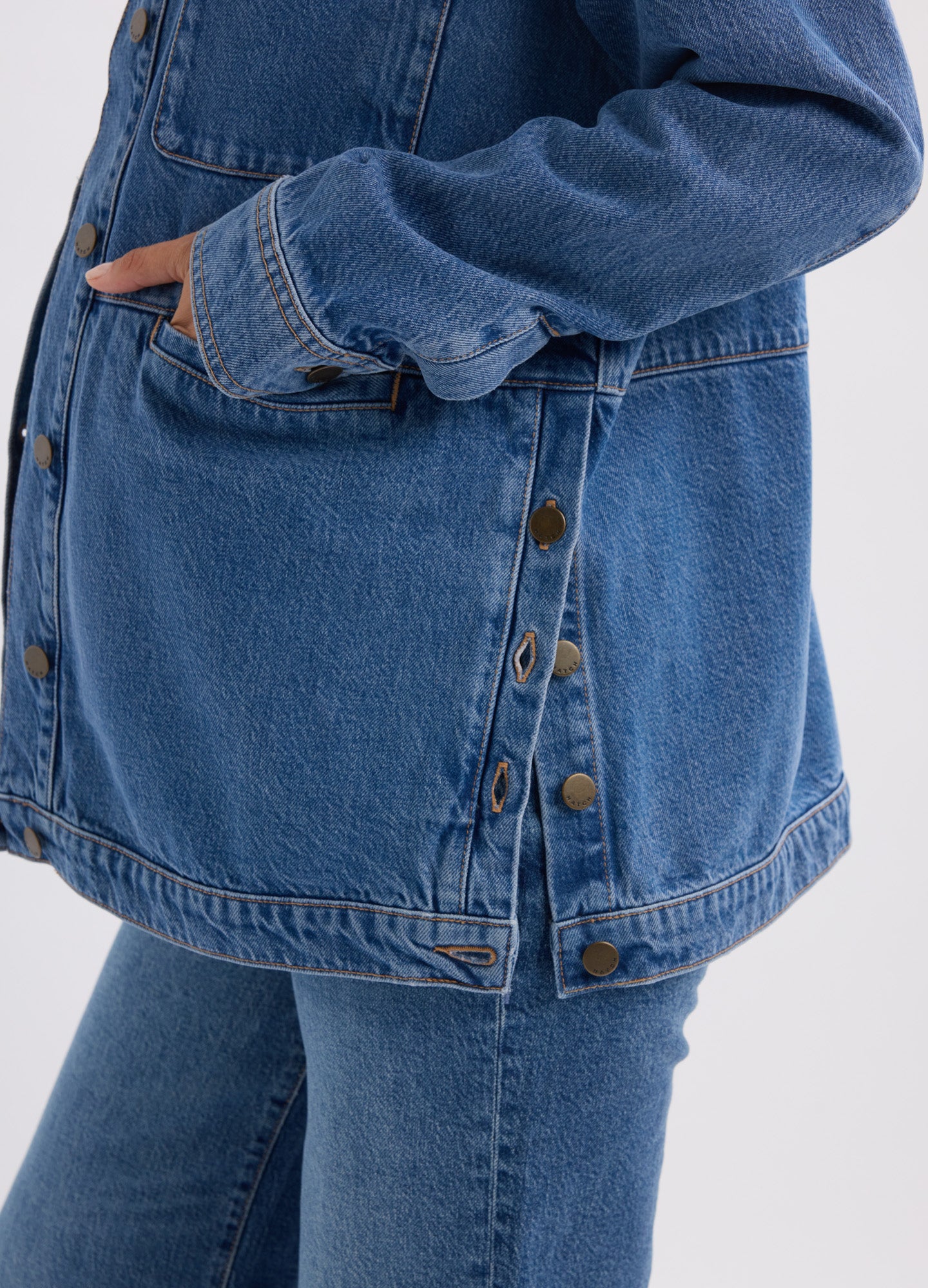 Blue denim maternity jacket with side snap buttons and roomy fit for pregnant belly.