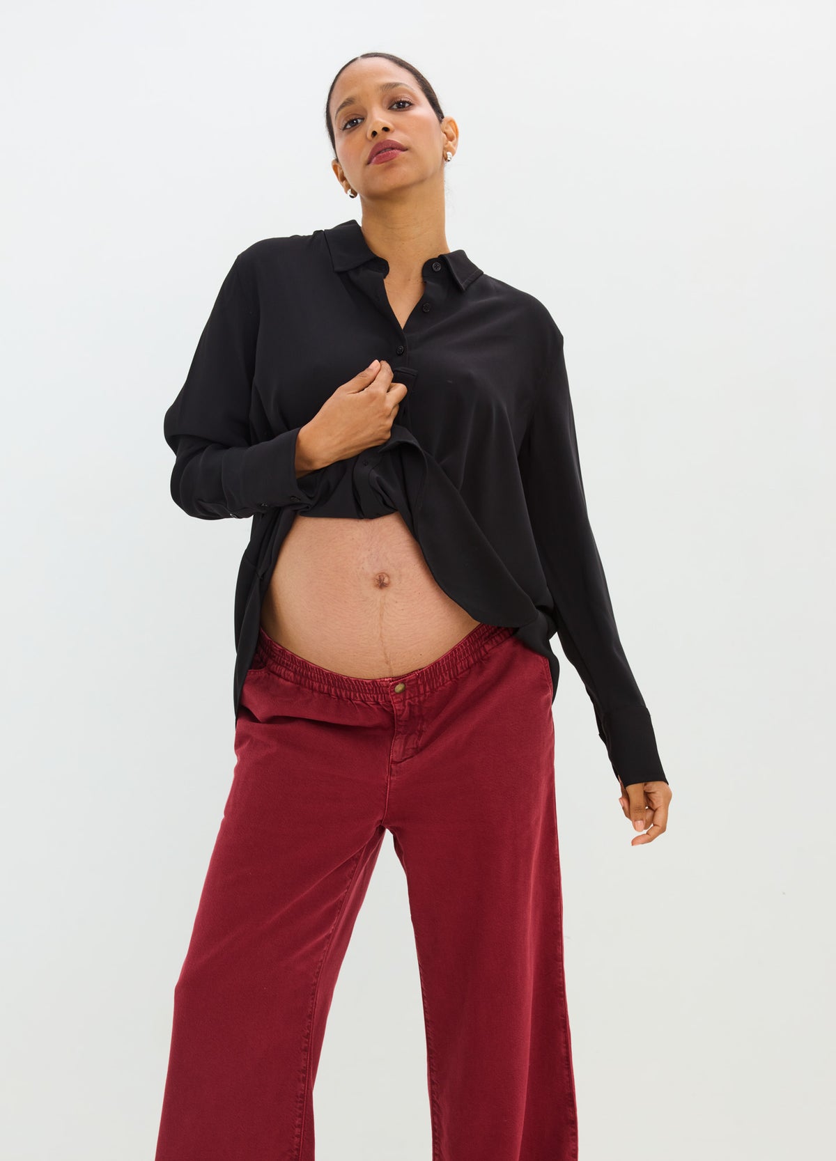 Black drapey button-down shirt with a relaxed fit and rolled cuffs, paired with burgundy trousers.