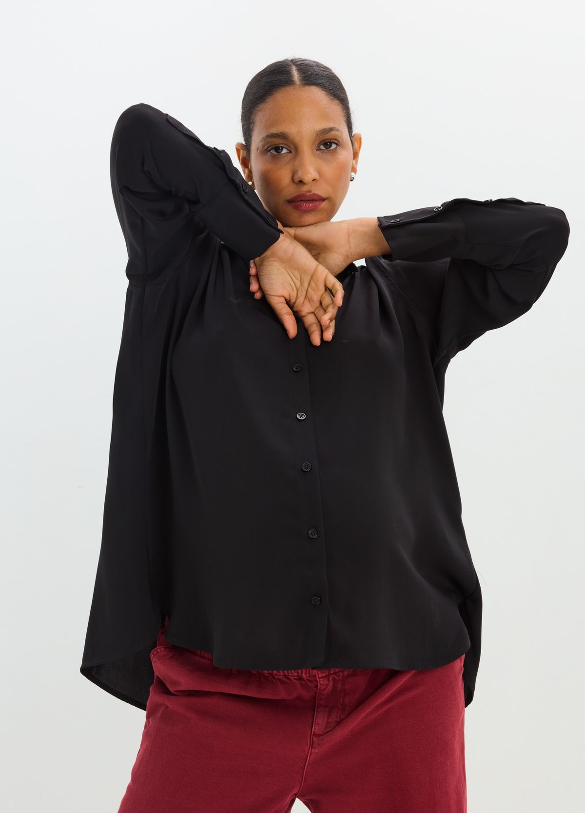 Woman wearing a black drapey button-down shirt with a relaxed fit, long sleeves, and a pointed collar.